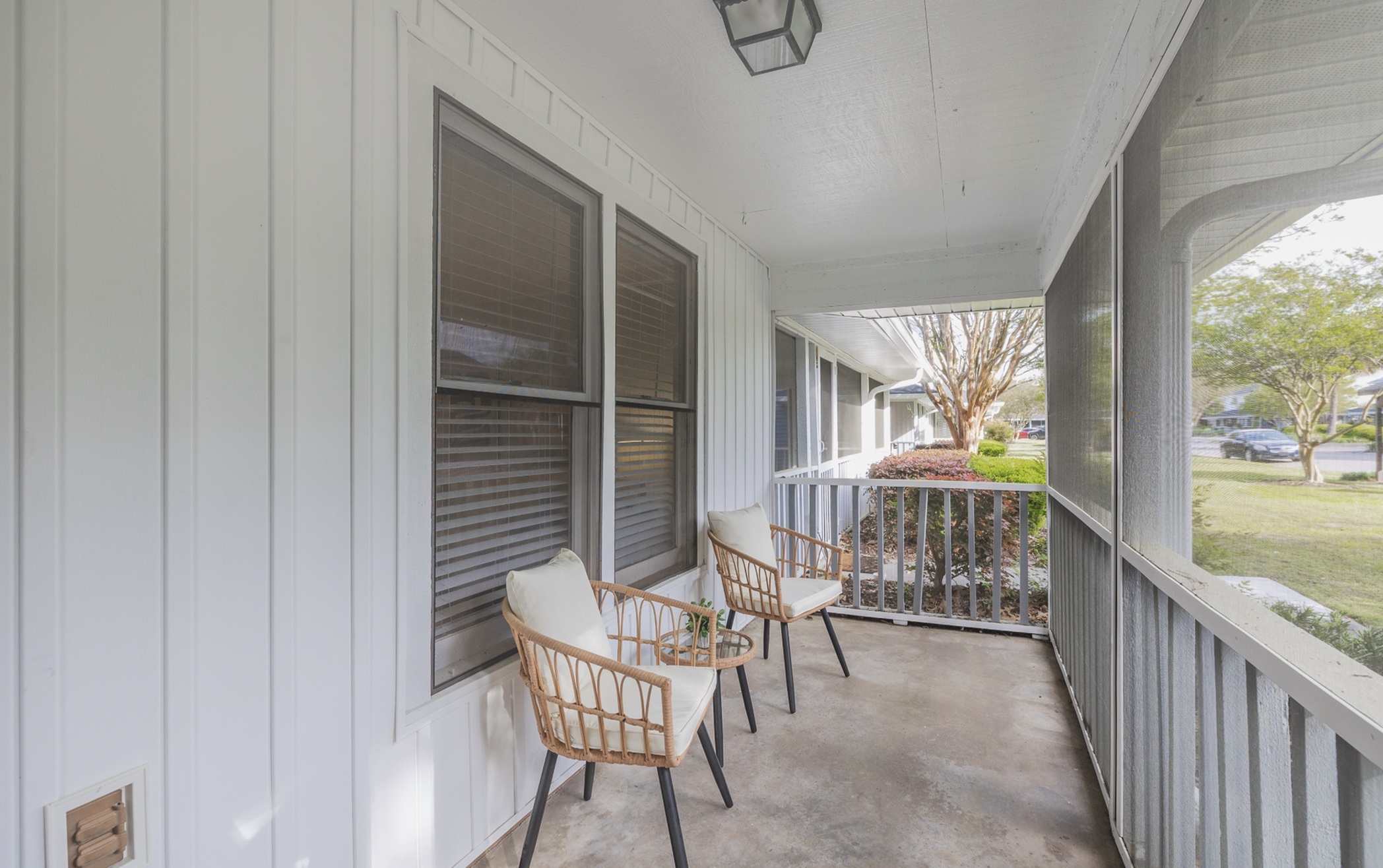 Charming porch with cozy wicker chairs and a serene view of lush greenery, ideal for relaxation and enjoying the outdoors.