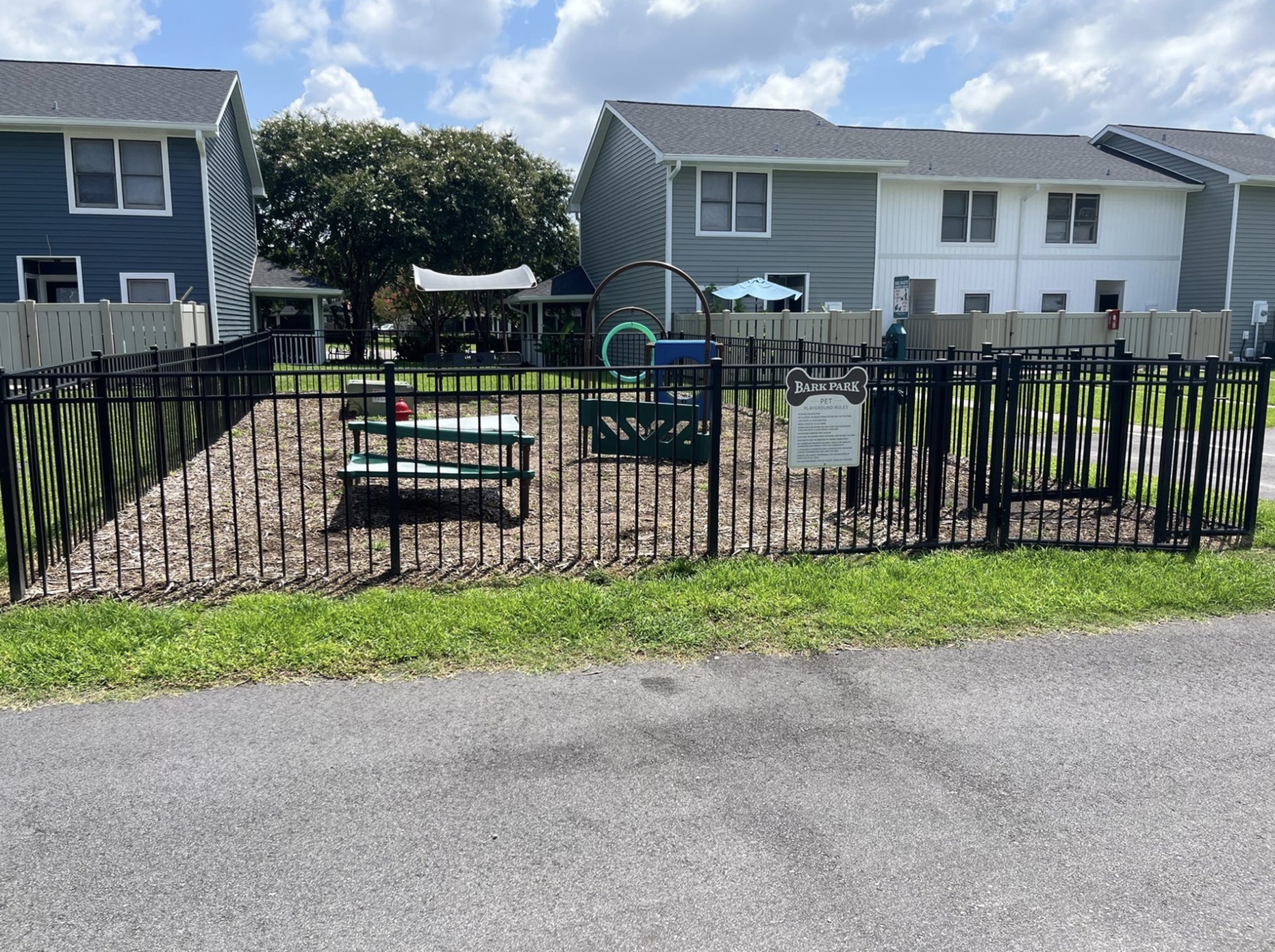 Charming fenced bark park featuring playful agility equipment in a serene residential setting.