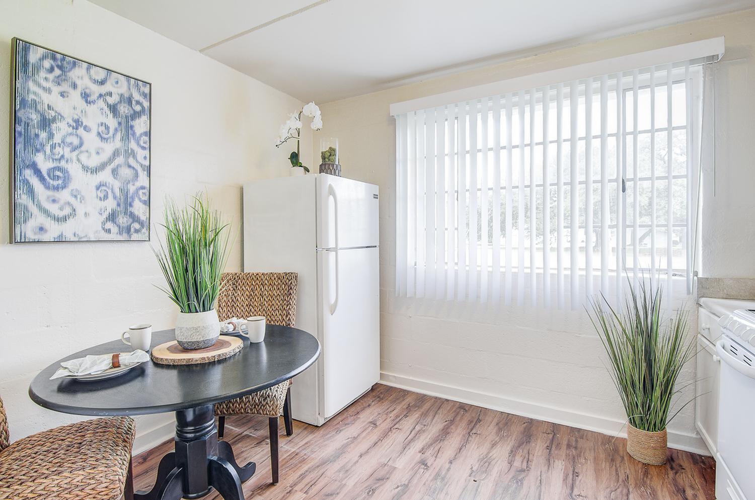 Bright kitchen nook with chic decor, cozy dining set, and modern appliances next to a large window.
