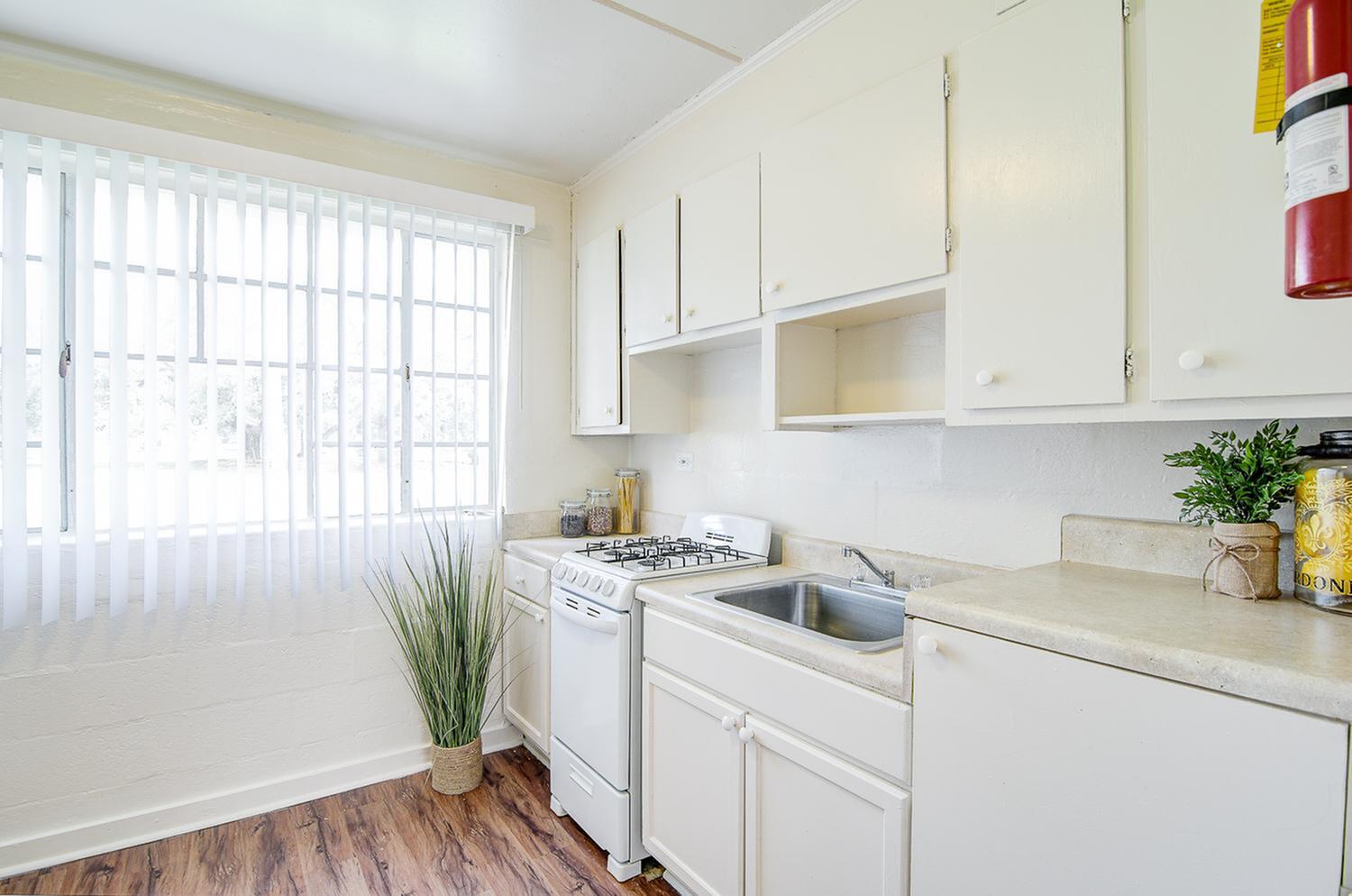 Bright and airy kitchen with modern appliances, abundant natural light, and elegant wood flooring accentuated by sleek white cabinetry.