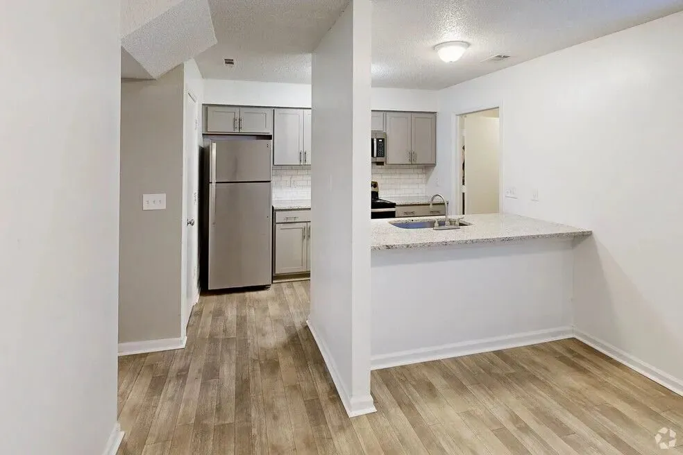 Modern kitchen with sleek stainless steel appliances, elegant granite countertop, and stylish wood flooring.
