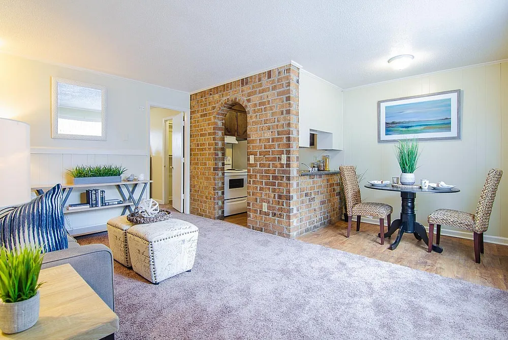 Inviting living space with stylish decor, featuring a cozy dining area and a charming brick-accented kitchen corner.