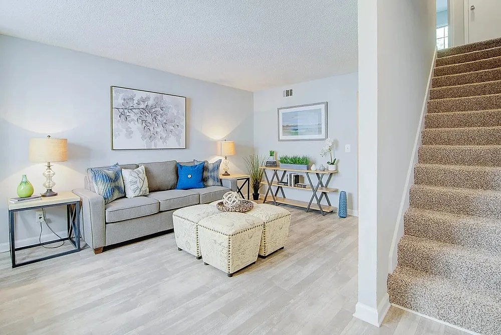 Inviting living room with modern decor, cozy grey sofa, stylish artwork, and natural light; ideal for relaxation and gatherings.