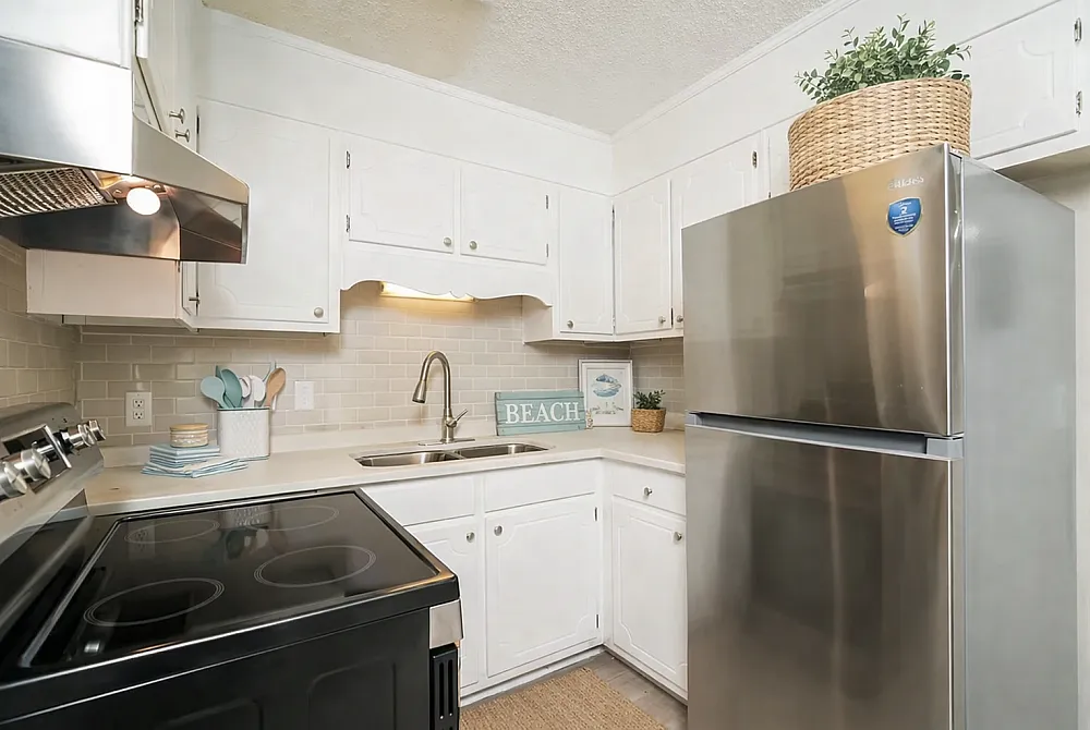 Bright and stylish kitchen with modern stainless steel appliances, chic white cabinetry, and elegant backsplash for a fresh coastal feel.