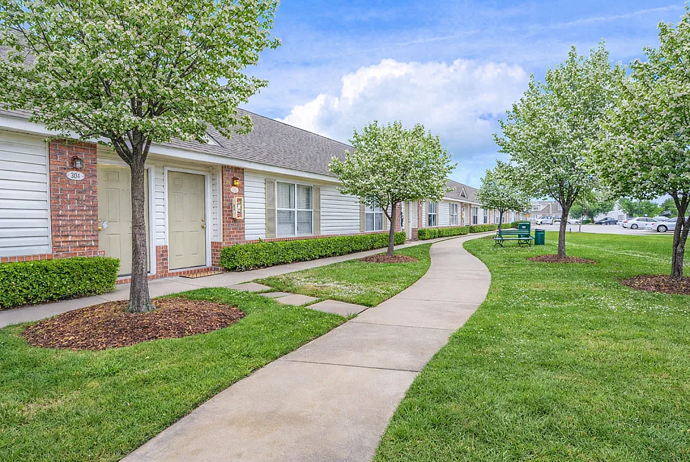 Charming suburban apartment complex with landscaped greenery, inviting pathways, and blooming trees.