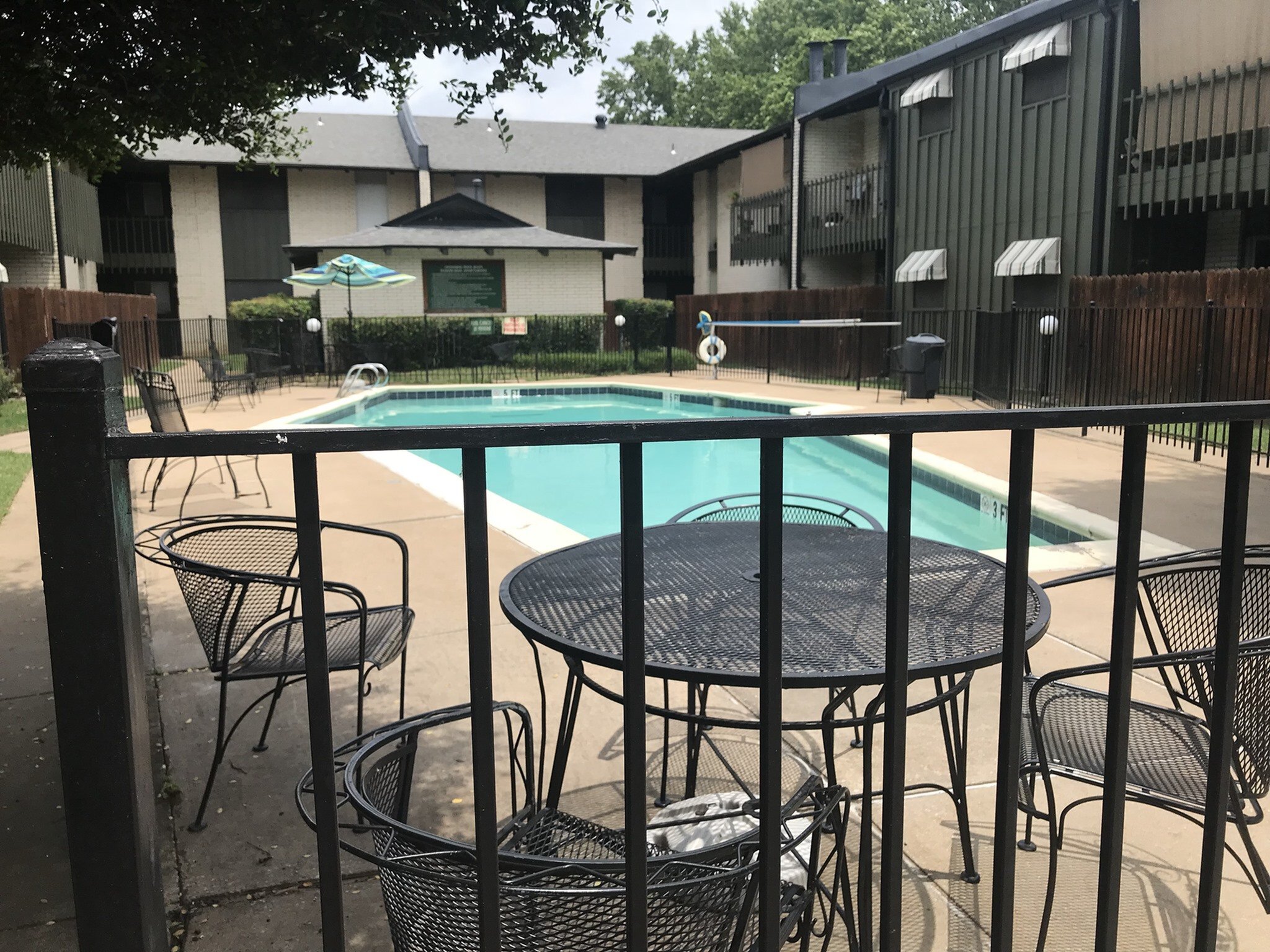 Charming apartment complex with a refreshing poolside view, featuring stylish outdoor seating and lush greenery for a perfect relaxation spot.