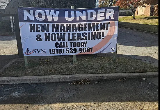 Engaging outdoor banner highlighting new management and leasing opportunities amidst a vibrant setting.