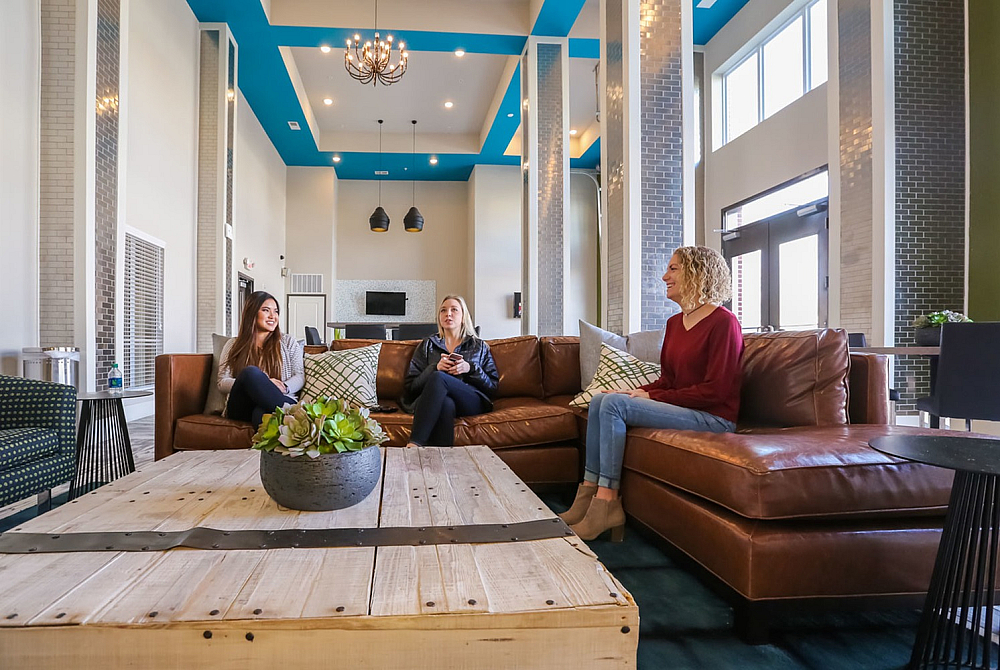 Inviting and stylish lounge area with a modern design, featuring comfortable leather seating, chic decor, and natural light through large windows.