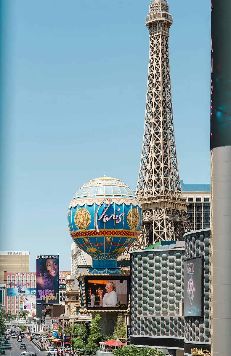 Vibrant Vegas cityscape featuring iconic replica of Eiffel Tower and colorful Paris balloon, bustling with activity and entertainment.