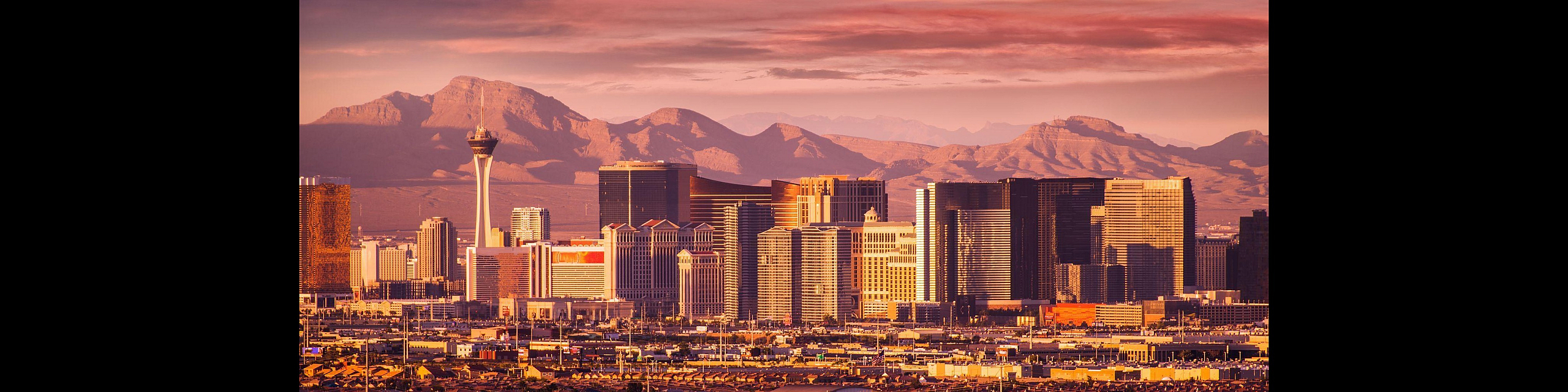Breathtaking panoramic view of a vibrant cityscape set against majestic mountains at sunset, showcasing iconic architecture illuminated by warm hues.