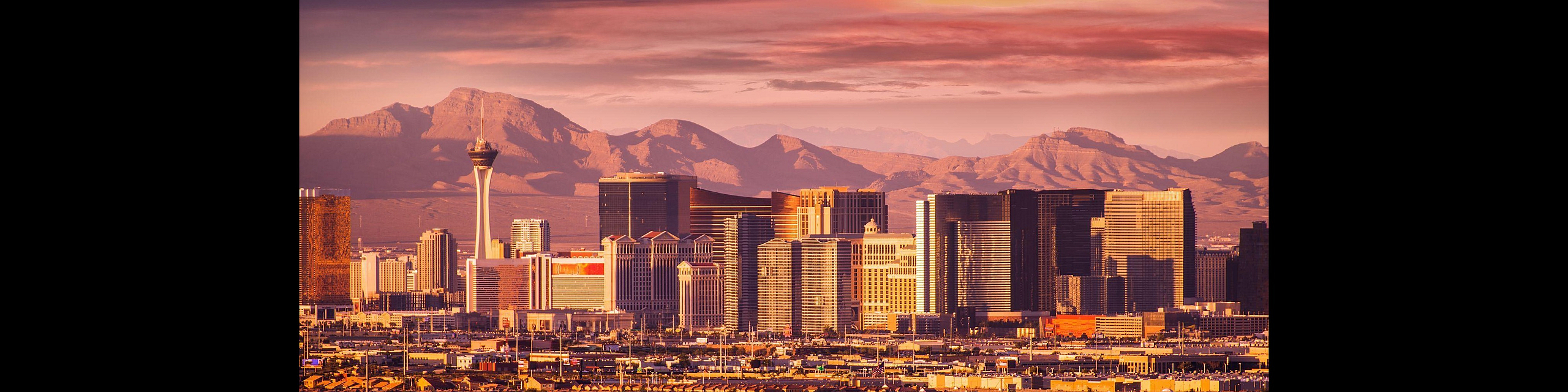 Breathtaking panoramic view of a vibrant city skyline with towering buildings set against a majestic mountain backdrop at sunset.