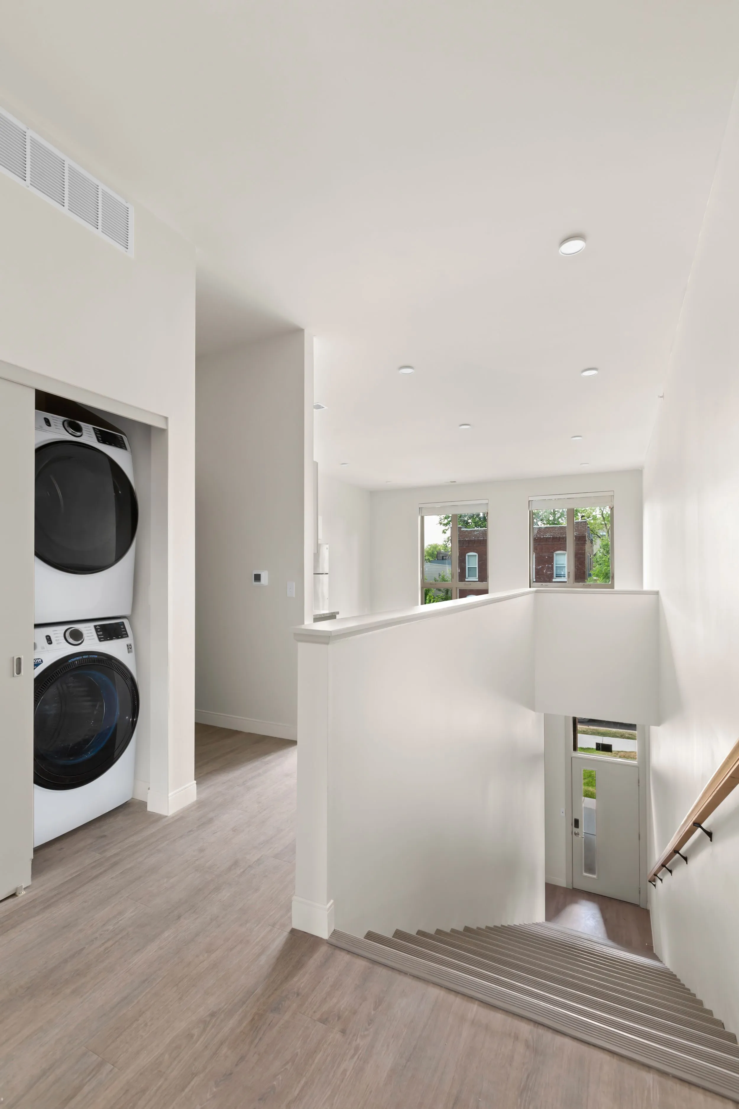 Bright interior showcasing a modern staircase and convenient in-unit laundry, complemented by large windows for natural light.