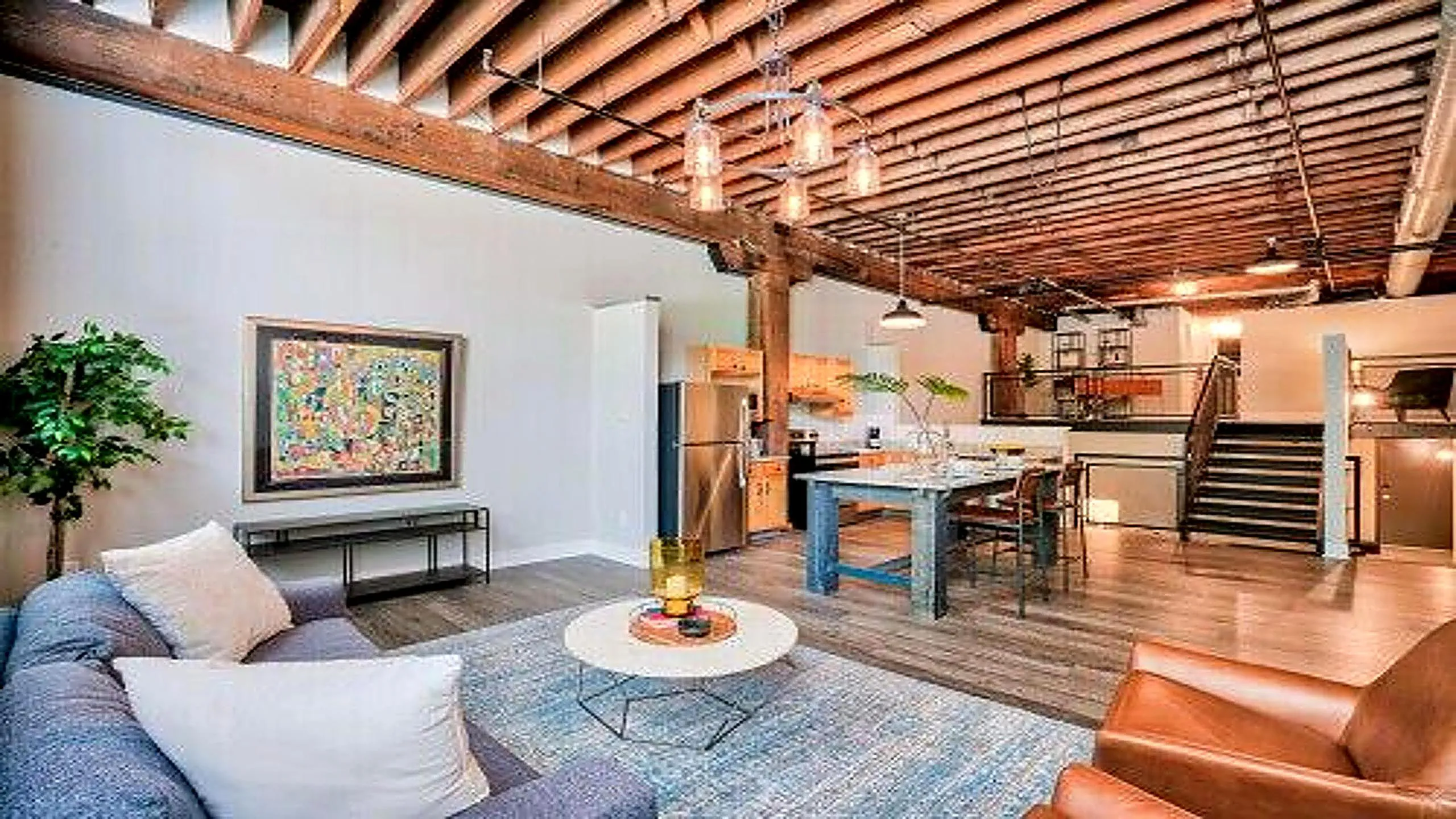 Chic industrial loft with exposed beams, modern kitchen, and open living area, perfect for urban living.