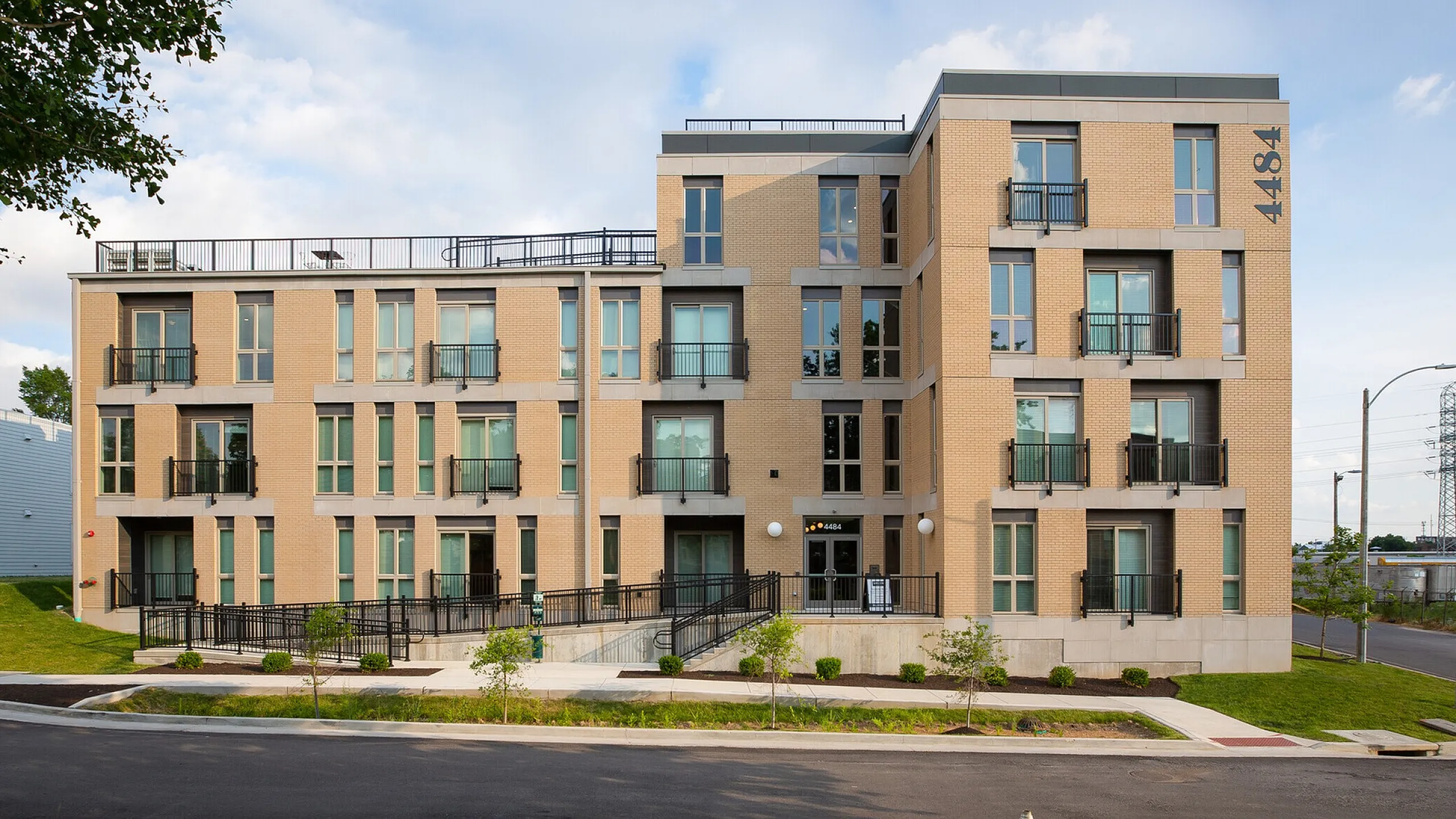 Modern urban apartment building with contemporary design, featuring large windows and private balconies, set in a vibrant neighborhood.