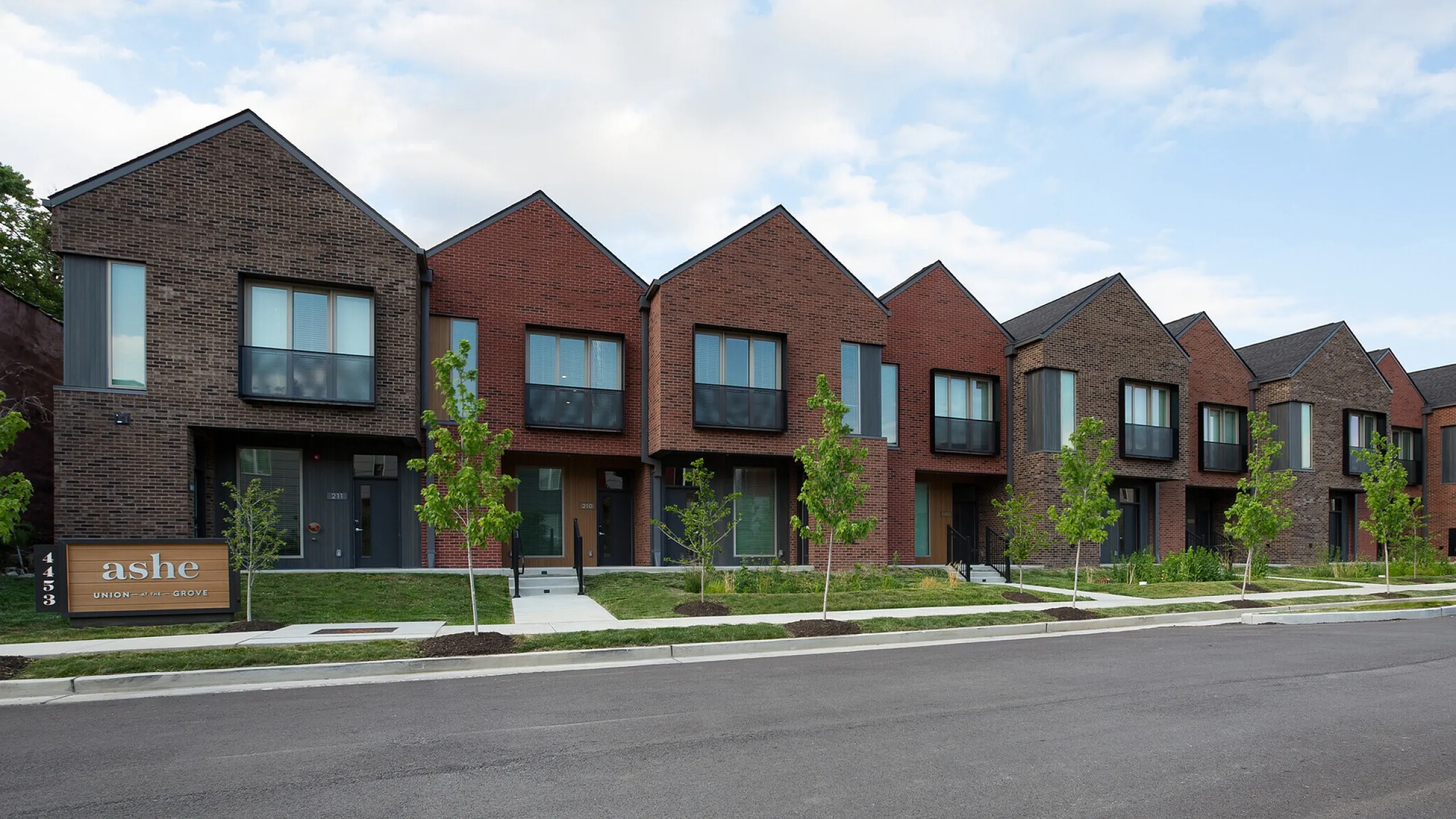 Elegant townhouse row featuring modern brick design and lush greenery at Ashe Union Grove.
