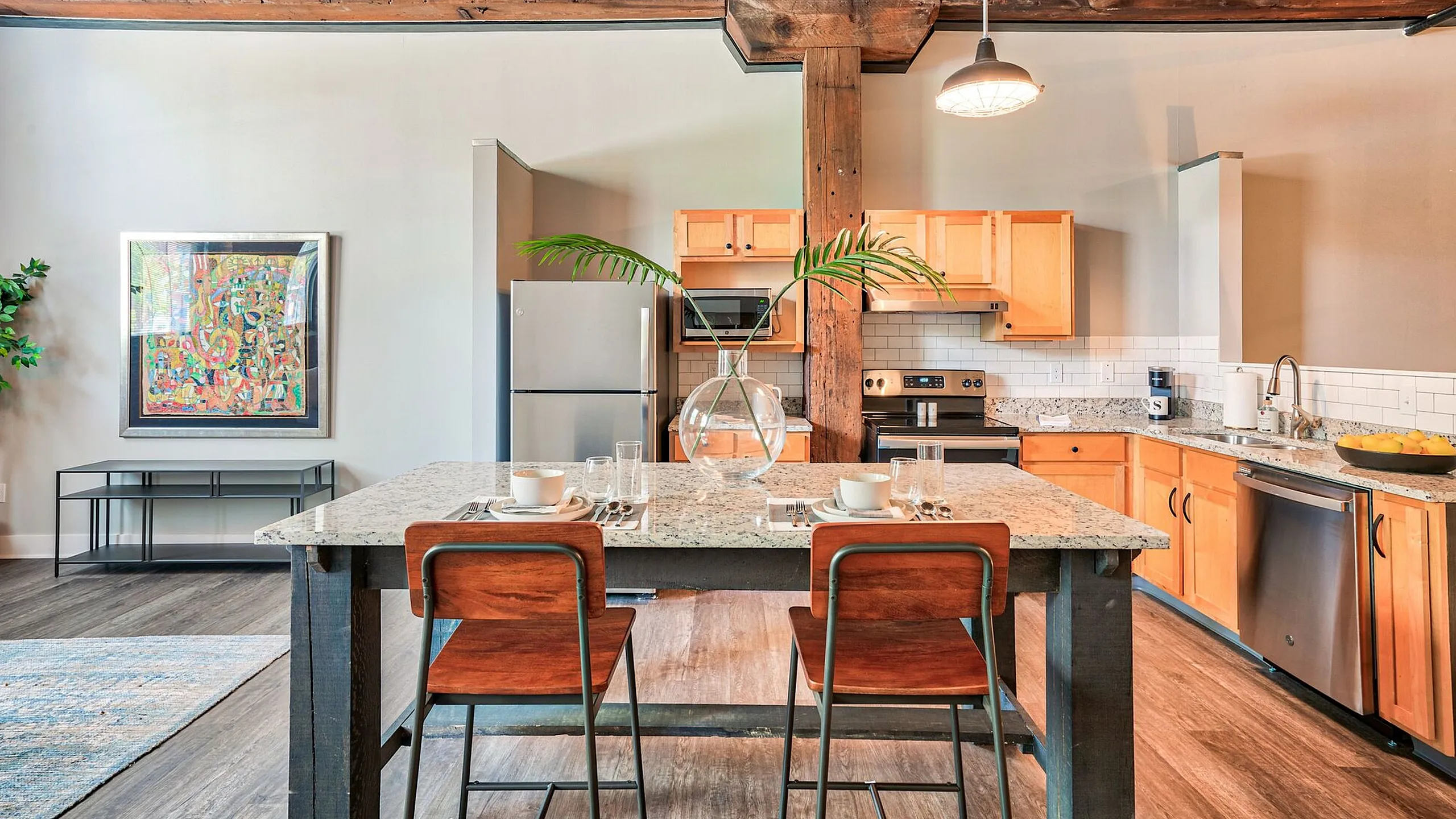 Chic industrial-style kitchen with exposed beams, featuring modern wooden cabinets and a sleek stone island with stylish bar seating.
