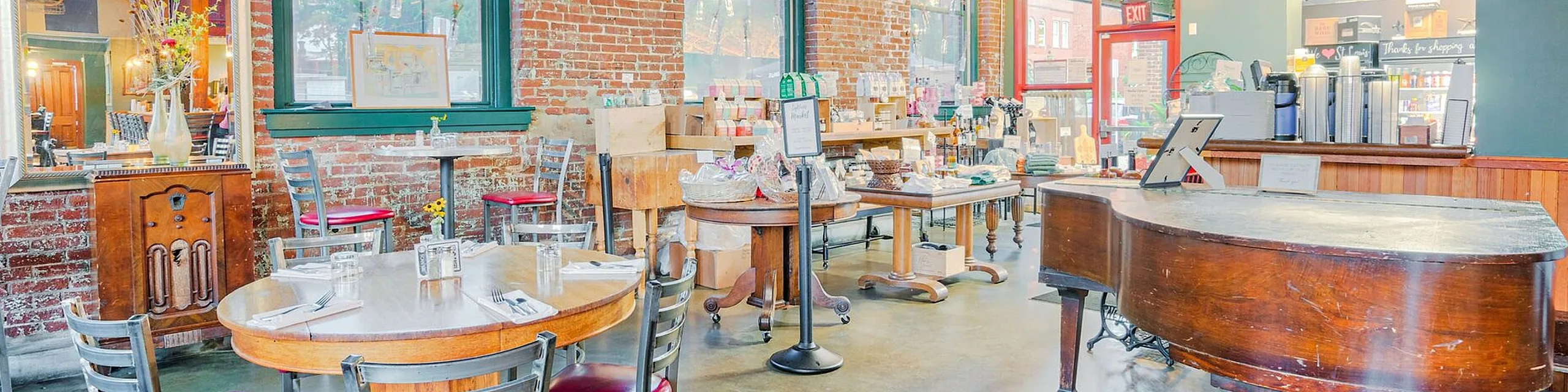 Charming cafe with exposed brick walls, vintage decor, and a cozy seating arrangement featuring a grand piano.