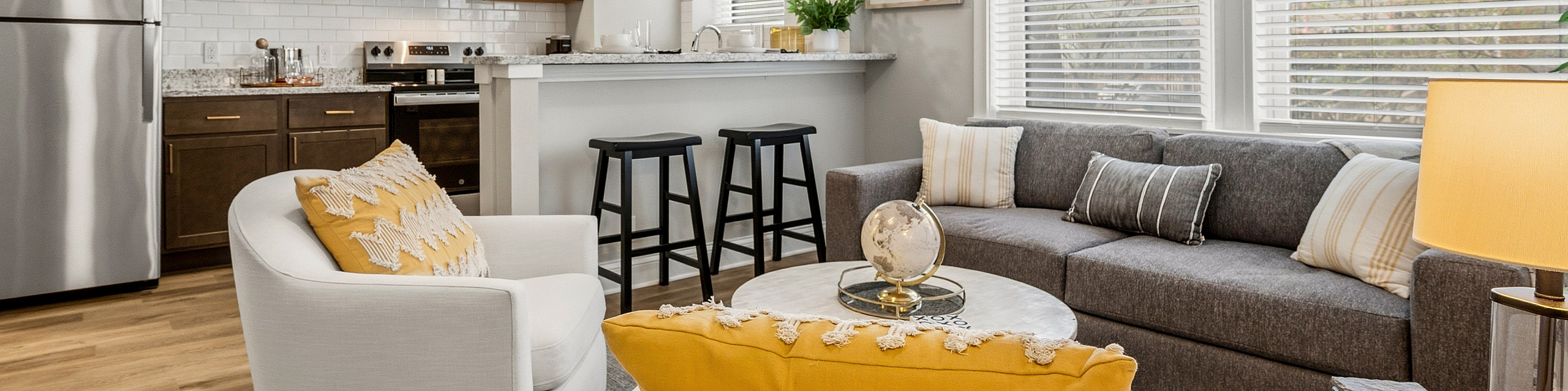 Bright and modern open-concept living space featuring a sleek kitchen with stainless steel appliances, cozy seating area, and large windows with natural light.
