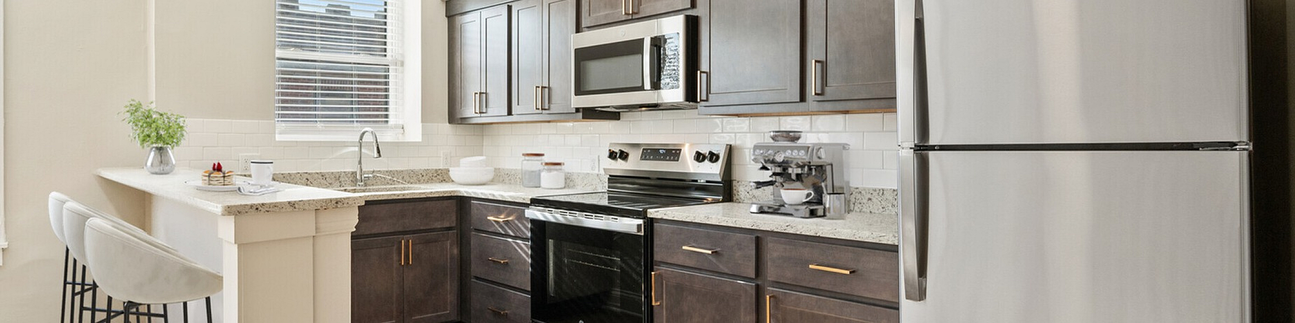 Bright and modern kitchen featuring sleek dark wood cabinets, stainless steel appliances, and an inviting breakfast bar with stylish seating.