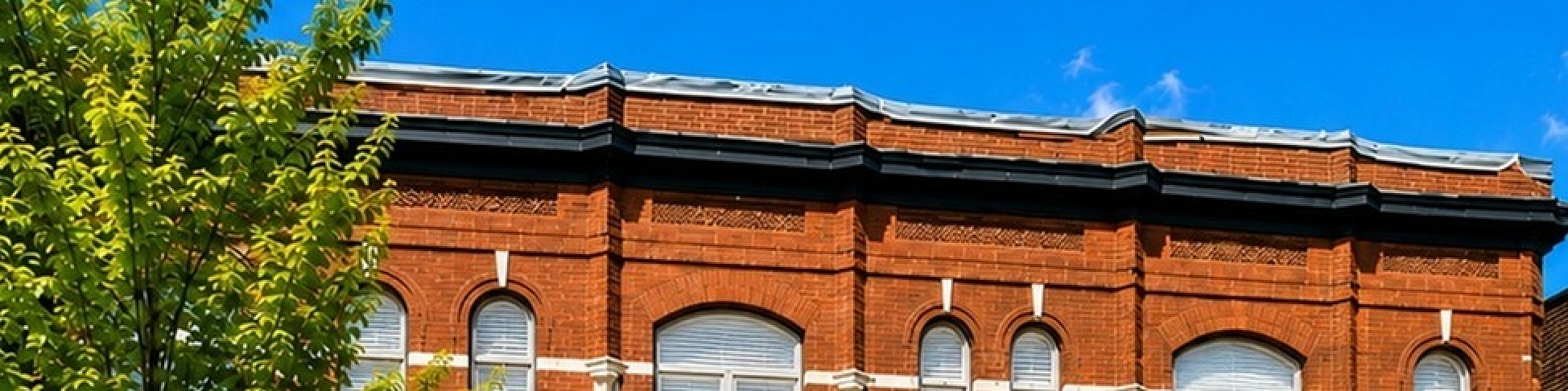 Charming historic red brick building with arched windows and welcoming entrances, perfect for urban living.