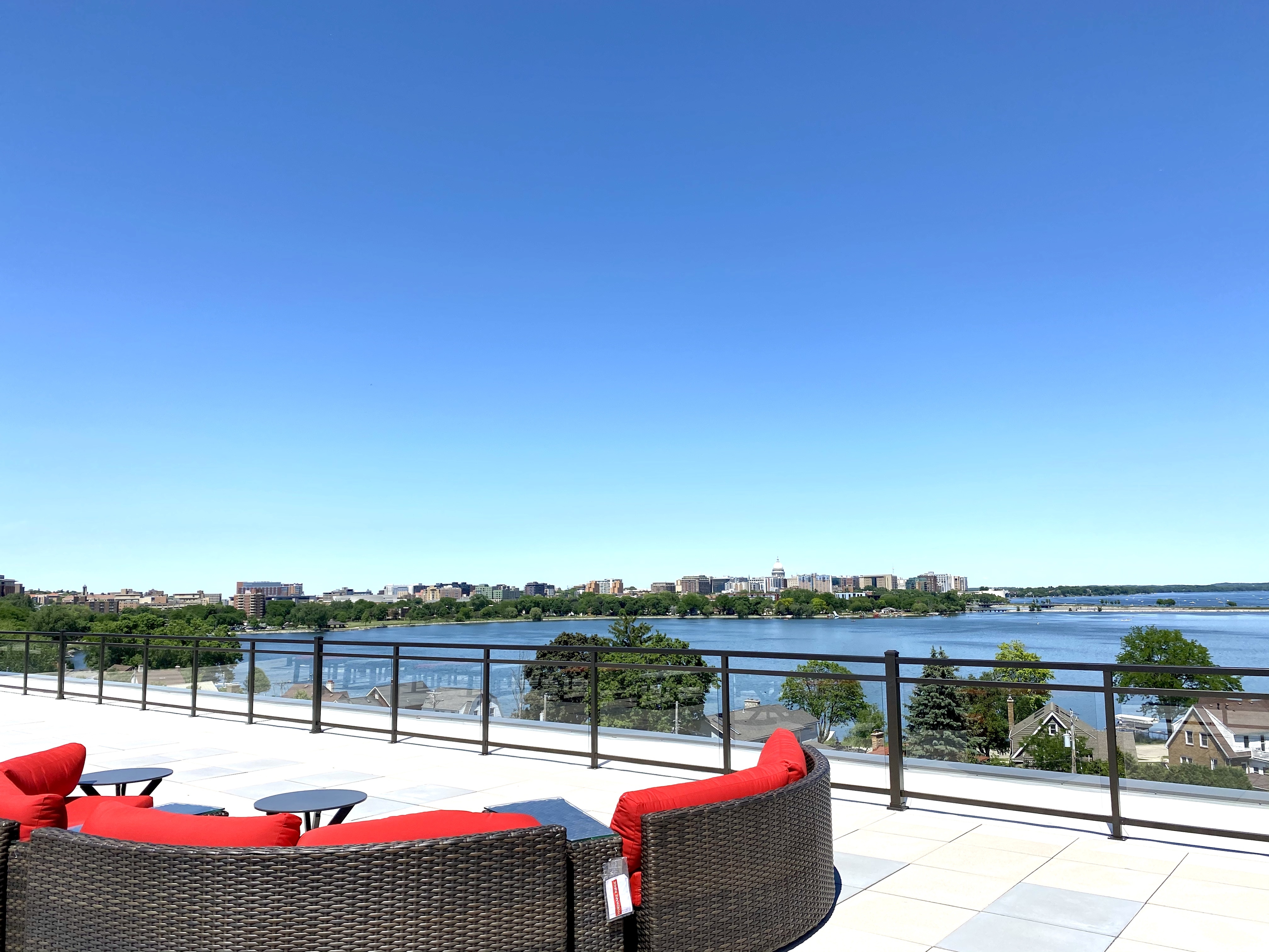 Stunning rooftop view featuring a panoramic city skyline and serene waterfront, complete with stylish outdoor seating.