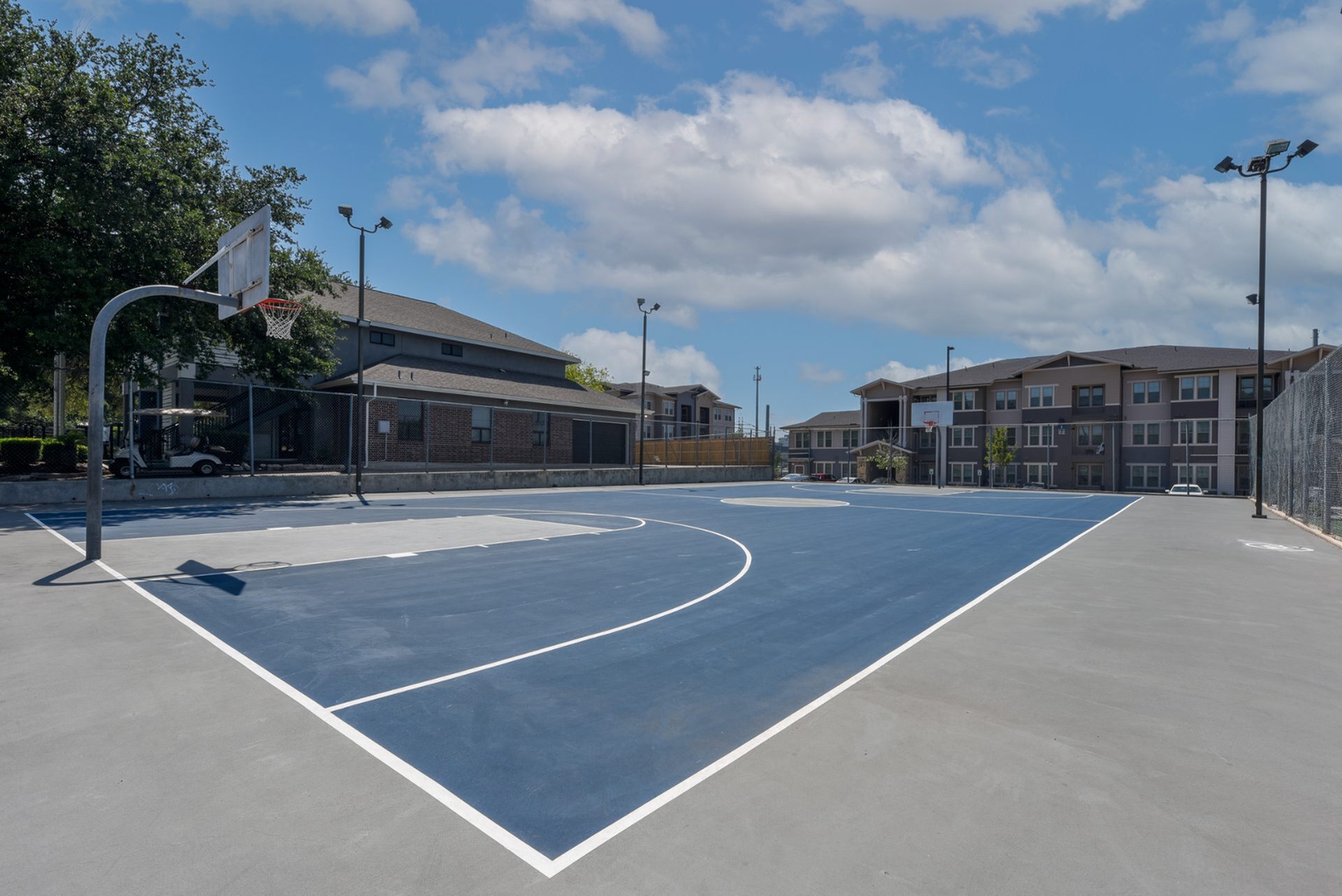 Sunny apartment complex with a modern outdoor basketball court, offering recreational amenities and a vibrant community atmosphere.