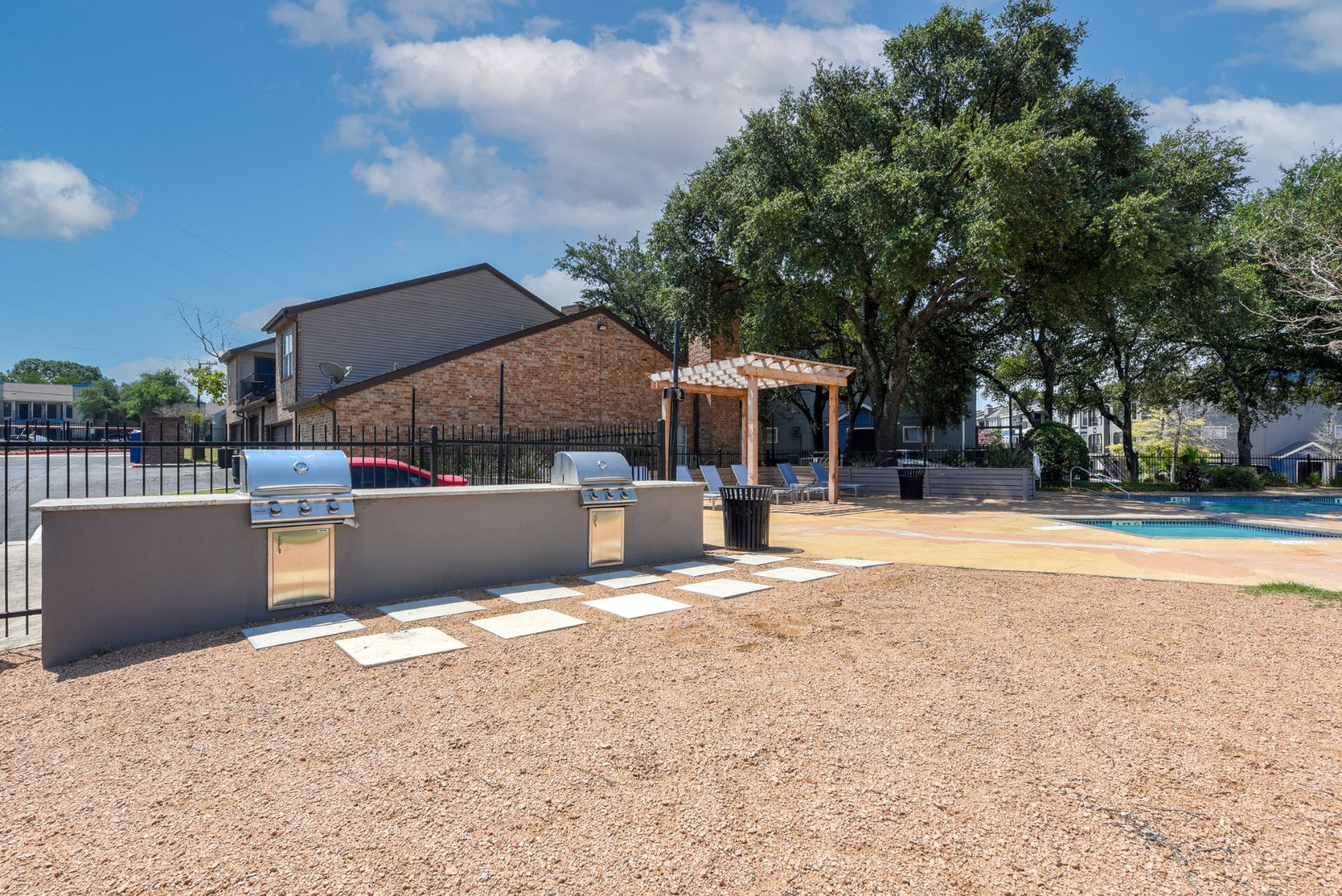 Inviting outdoor space with BBQ grills, cozy pergola seating, and sparkling pool, perfect for relaxation and entertaining.
