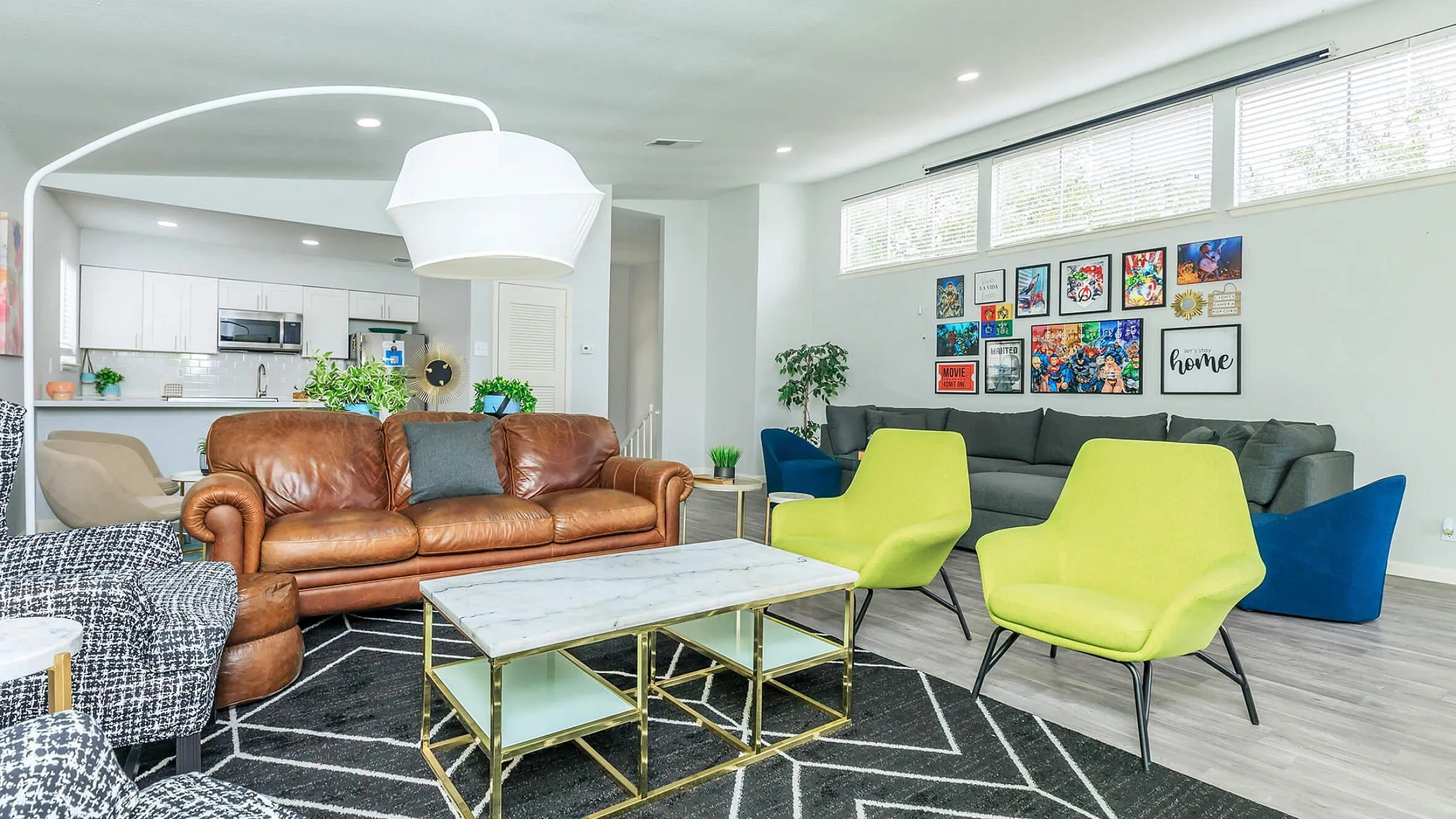 Bright and inviting living room with modern decor featuring leather and patterned seating, vibrant green chairs, a sleek marble coffee table, and a gallery wall of colorful artwork.