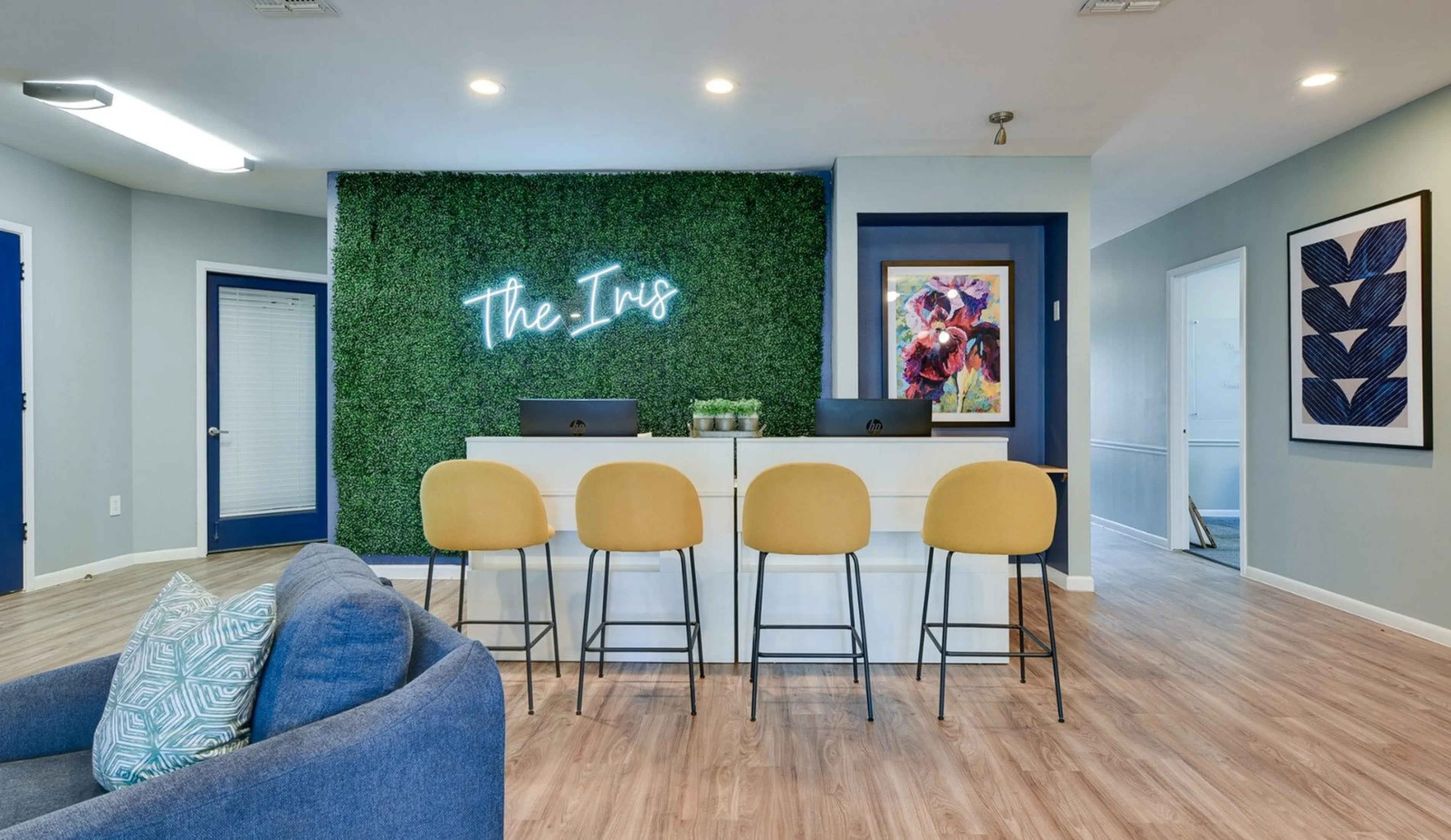 Modern office space with stylish design featuring a green wall accents, chic yellow chairs, and vibrant artwork at The Iris.