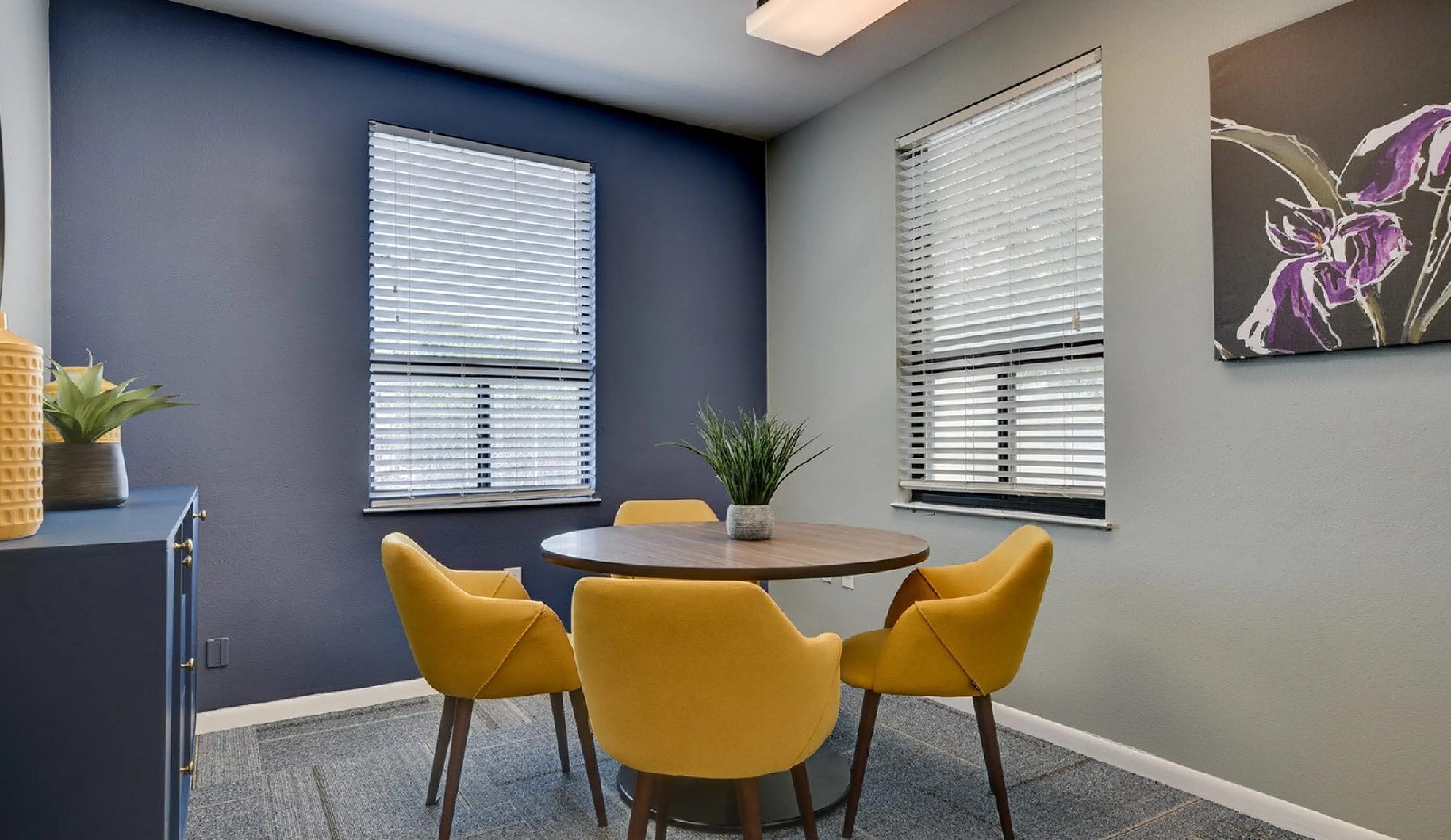 Modern dining nook featuring vibrant yellow chairs and a sleek round table, accentuated by stylish decor and soft natural light.