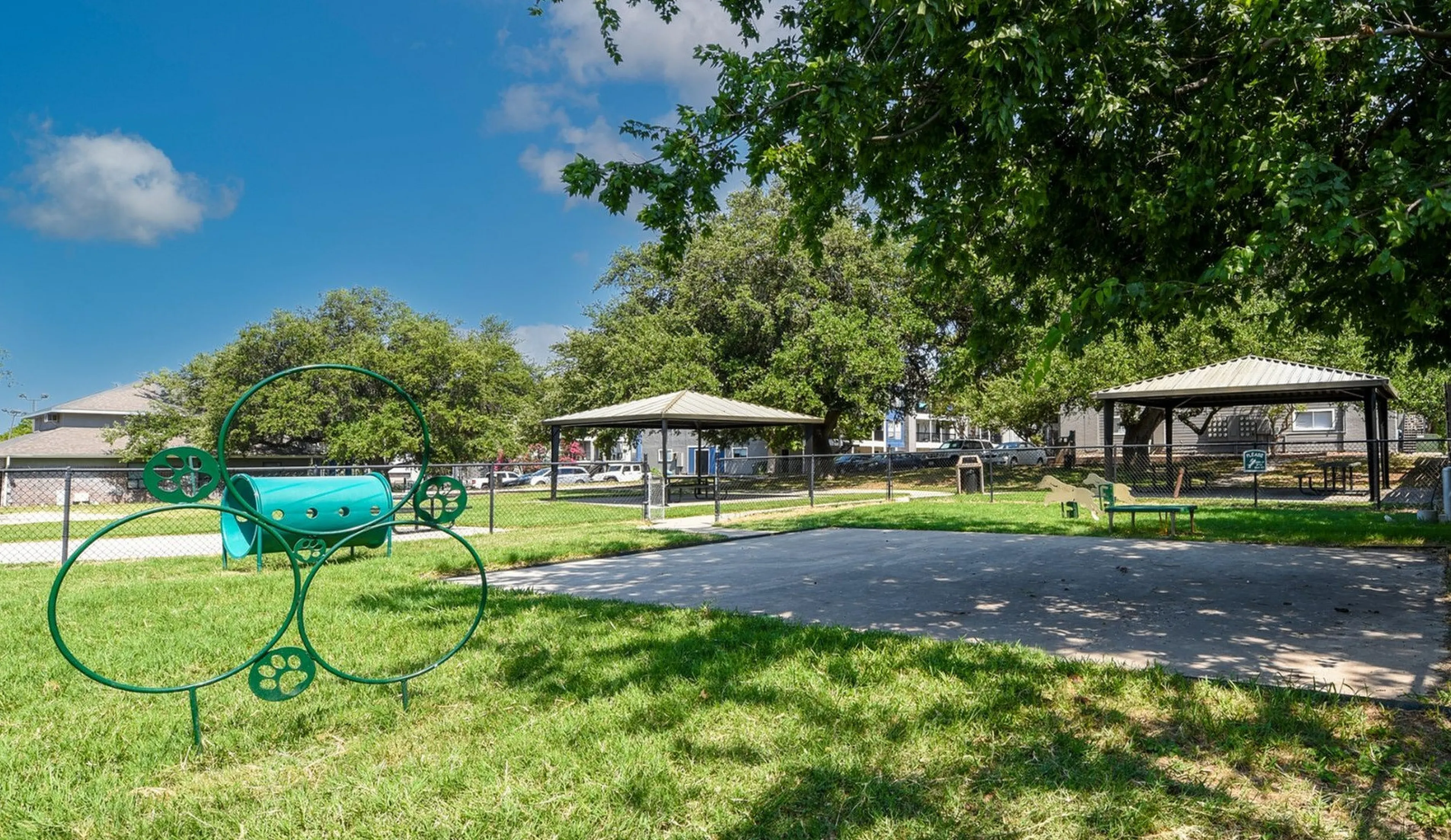 Inviting outdoor community park showcasing lush green lawns, modern pet-friendly play area, and shaded picnic gazebos under a bright blue sky.