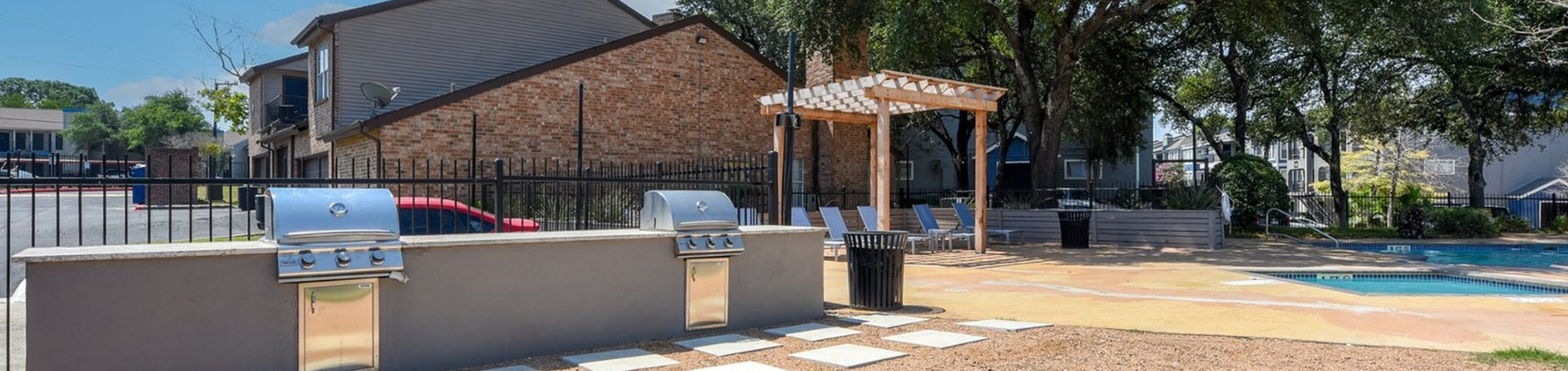 Inviting outdoor space featuring modern grills, a charming pergola, and a serene poolside area surrounded by lush greenery.