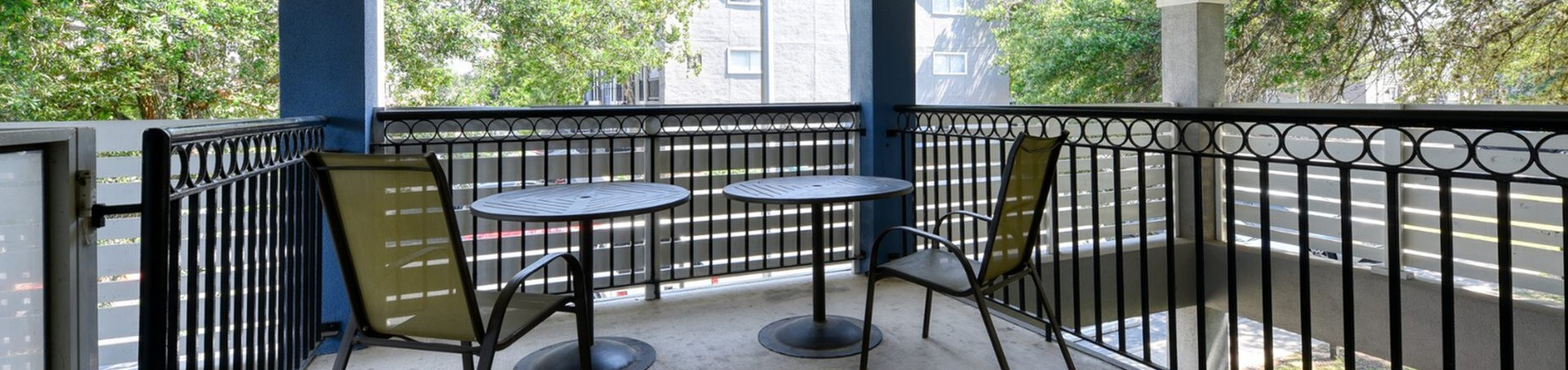 Charming covered balcony with stylish railings, offering a serene outdoor seating area surrounded by lush greenery.