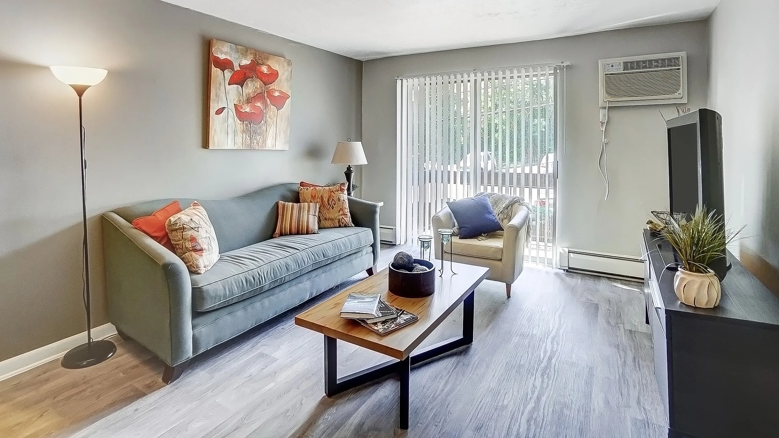 Cozy living room with modern decor, featuring a plush sofa, elegant artwork, and abundant natural light streaming through large windows.