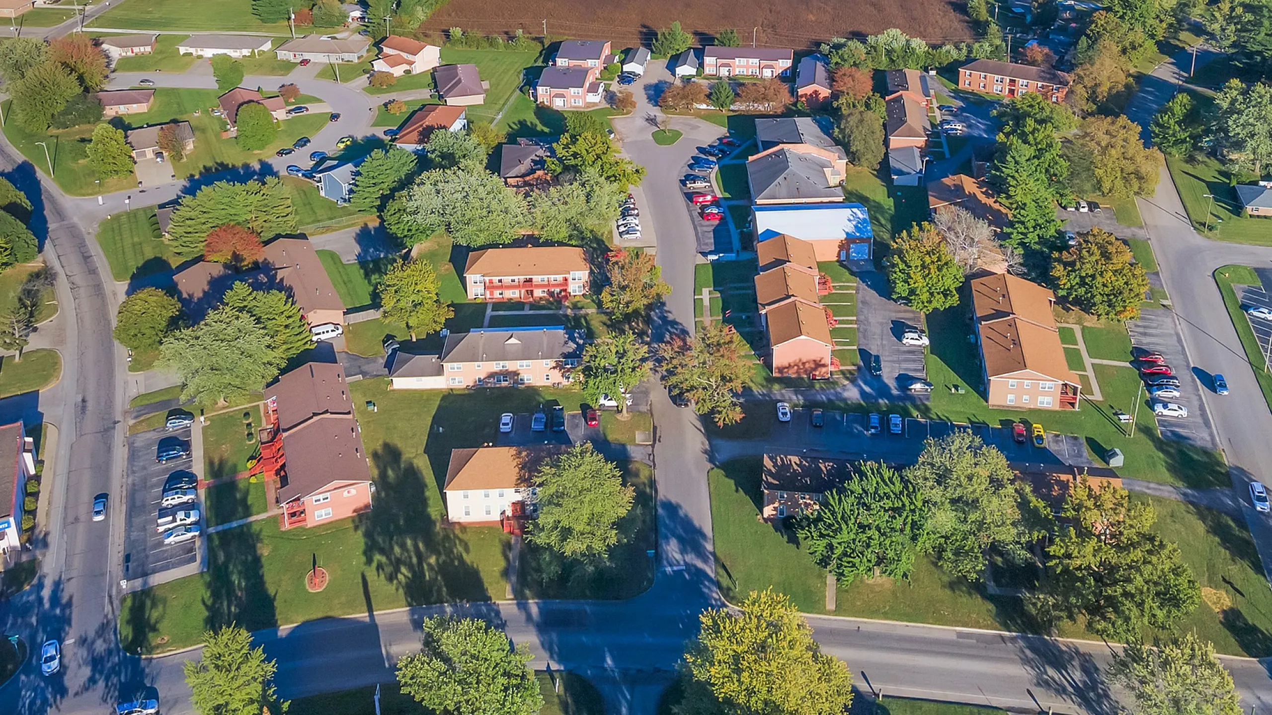 Charming aerial view of a vibrant suburban neighborhood with lush greenery, spacious homes, and convenient amenities.