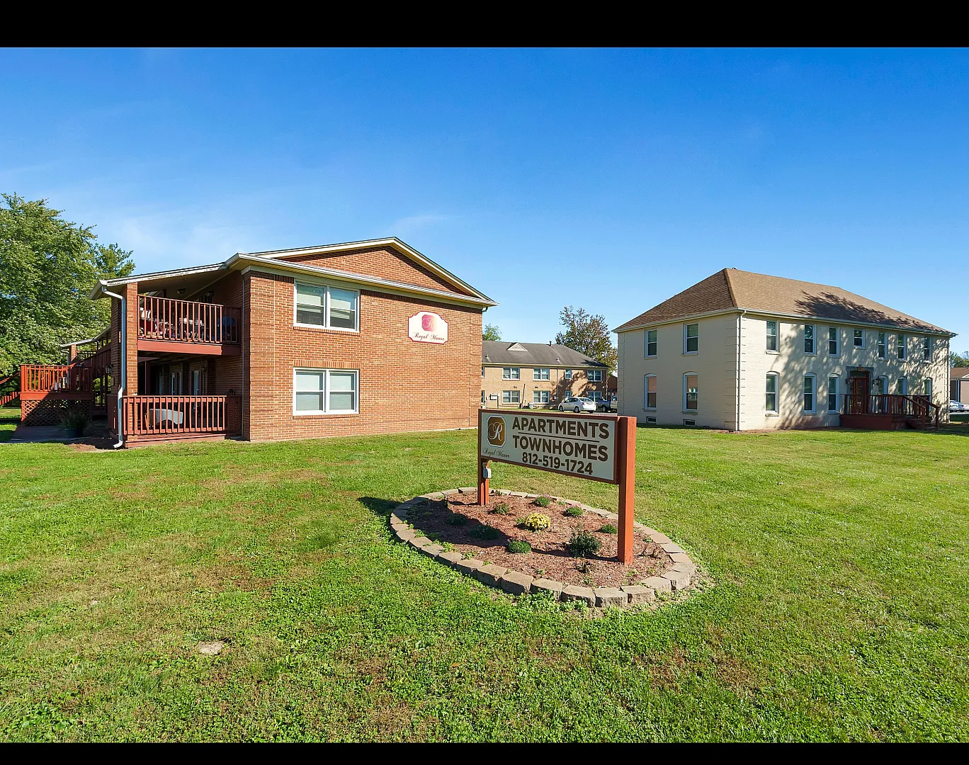 Charming brick apartments with lush green lawns and inviting balconies, perfect for modern living.