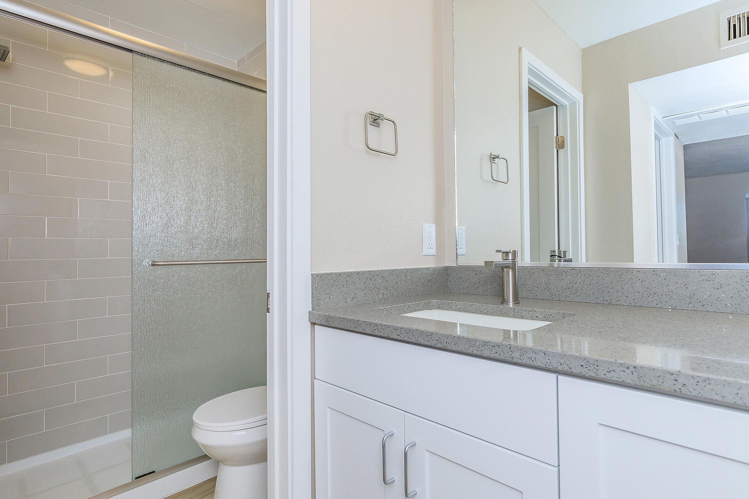 Elegant bathroom featuring sleek gray countertops, modern fixtures, and a glass-enclosed shower.
