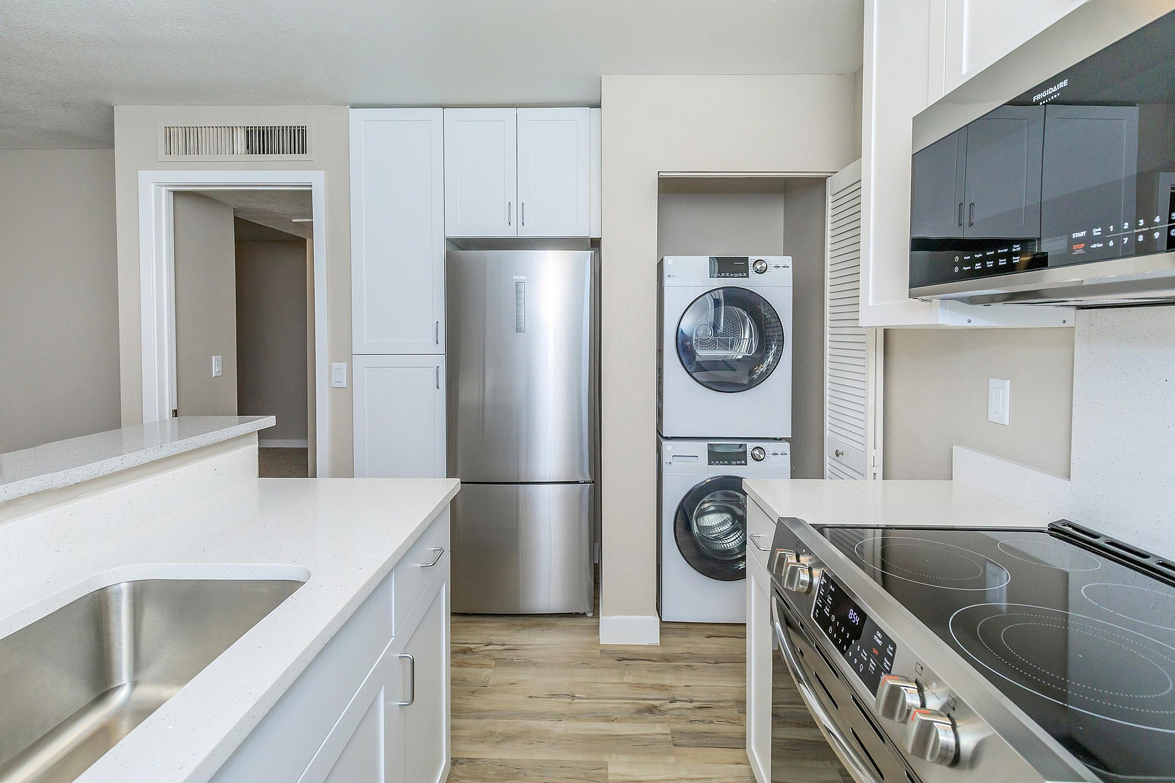 Modern kitchen with sleek stainless steel appliances, elegant countertops, and in-unit stacked washer and dryer.