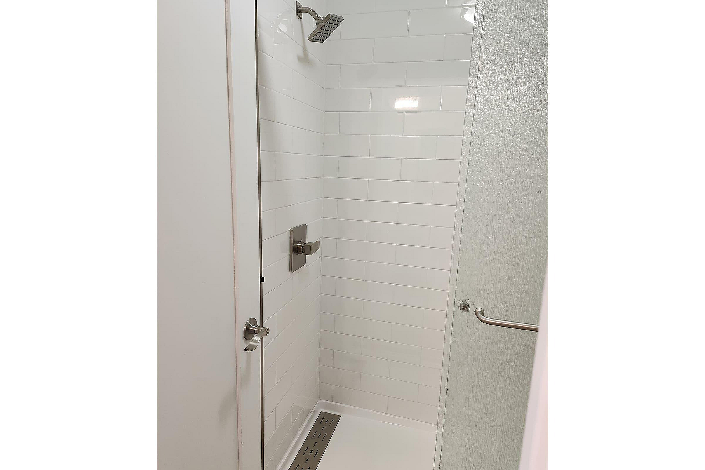 Elegant modern shower with sleek white tiles and minimalist fixtures for a luxurious bathroom experience.