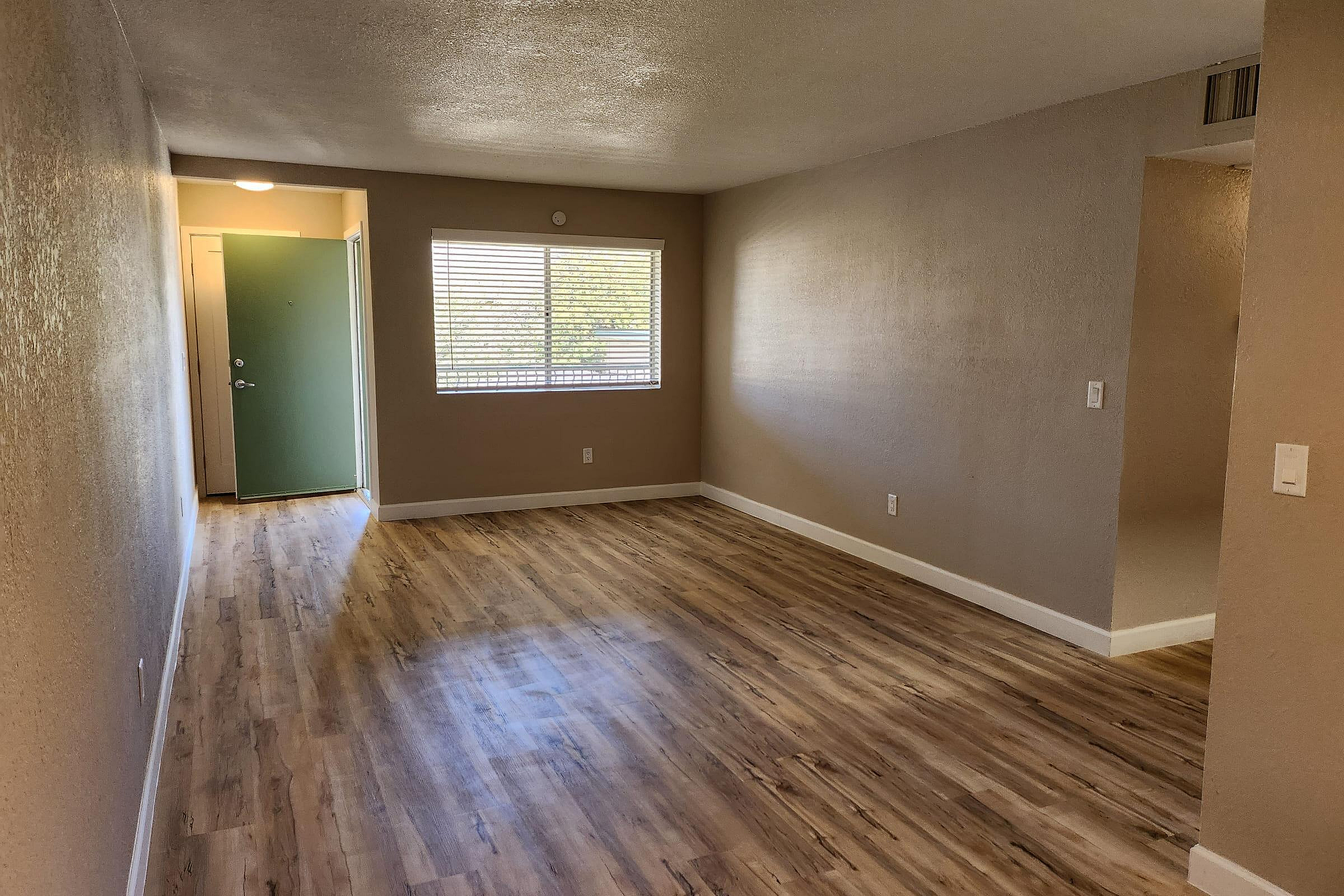 Bright and inviting entryway with elegant hardwood floors and soft natural light streaming through large windows.
