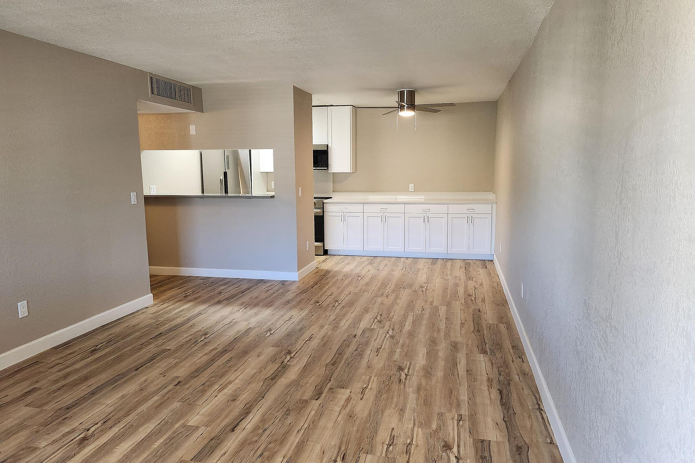 Bright and inviting open-concept living area featuring sleek wood flooring and a modern kitchen with ample cabinetry.