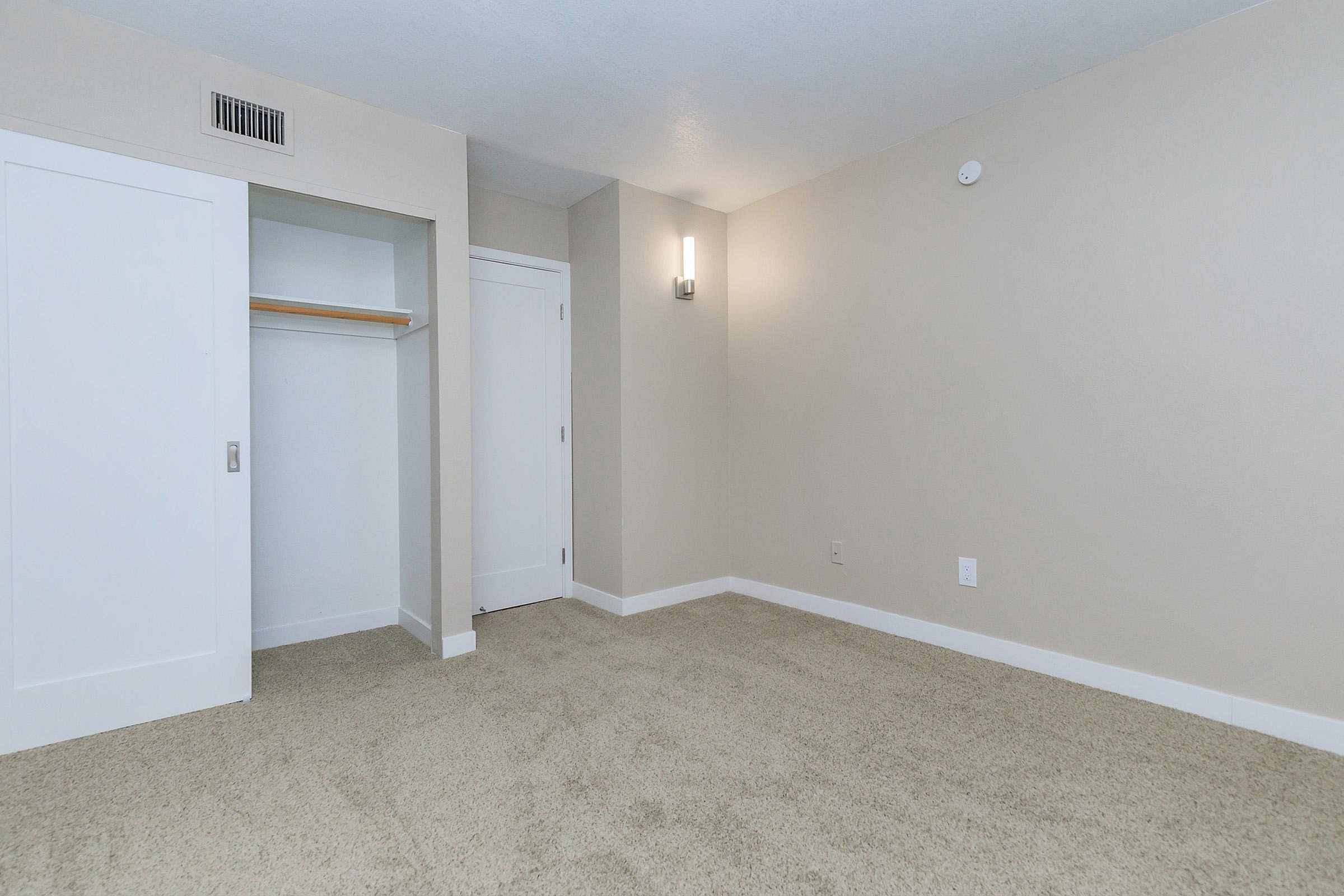 Bright and spacious room with plush carpeting, sleek built-in closet, and modern lighting.