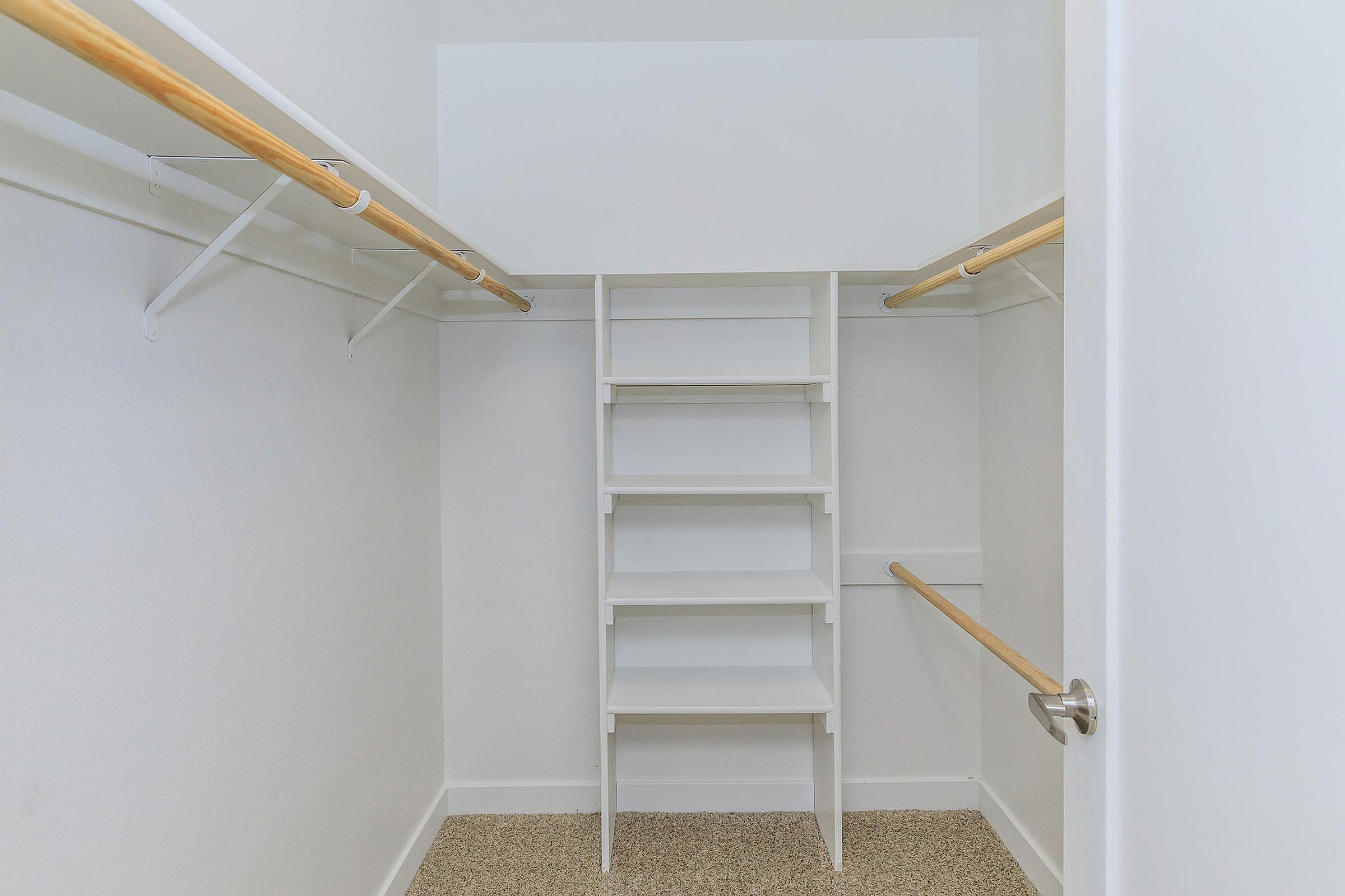 Spacious walk-in closet with built-in shelving and dual hanging rods, offering ample storage solutions.