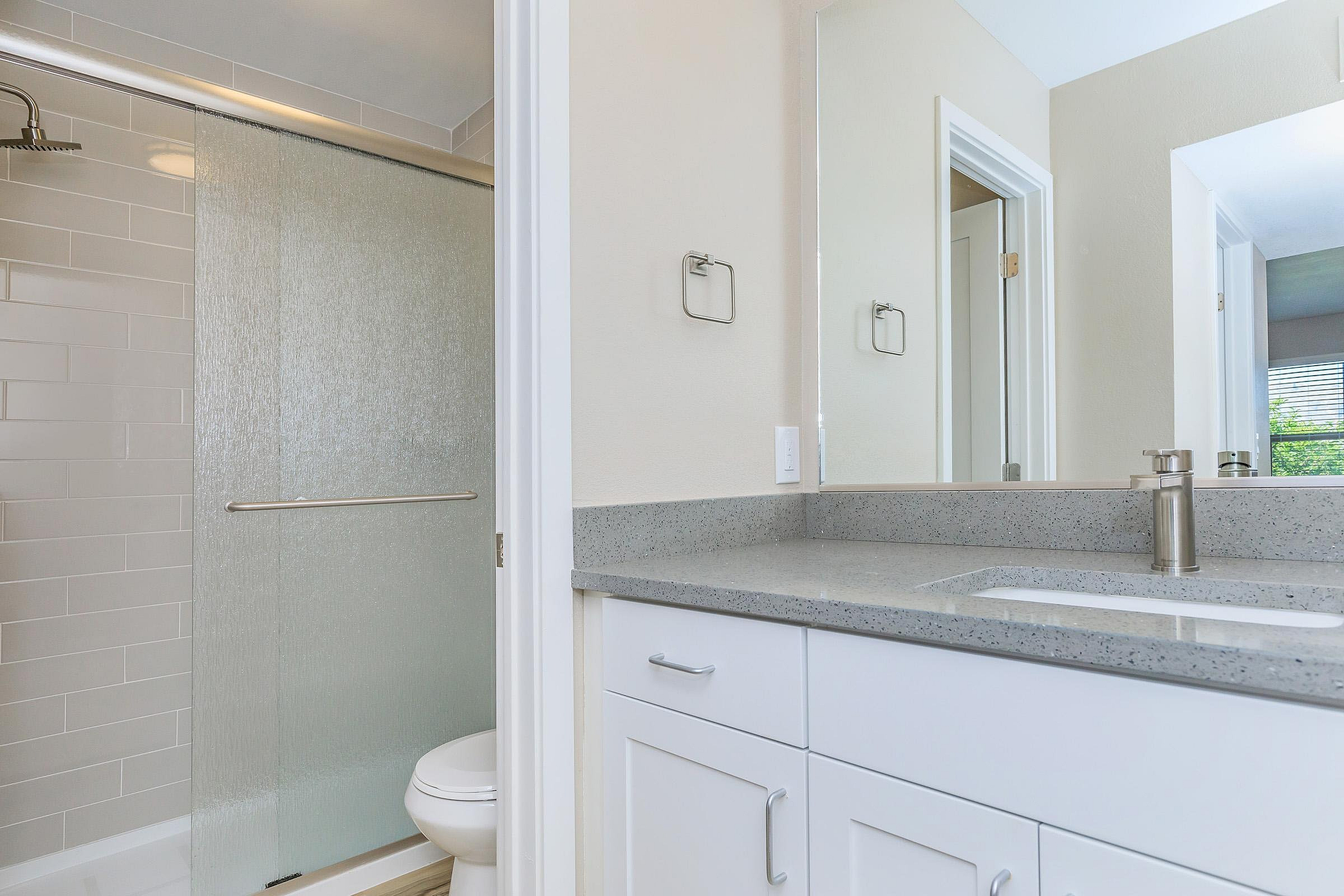 Elegant modern bathroom with a sleek gray countertop, spacious vanity, and a stylish glass-enclosed shower.