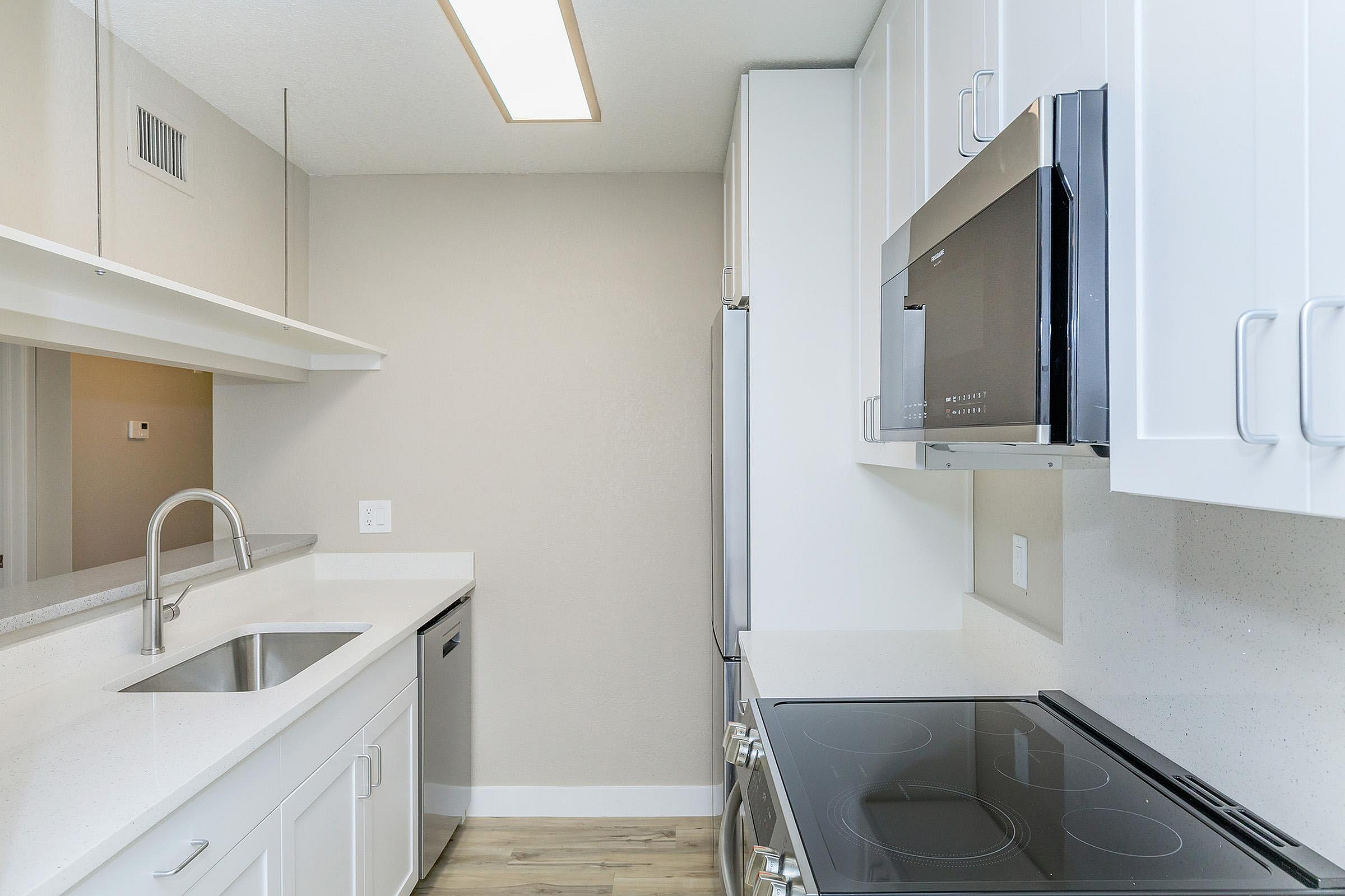Modern kitchen with sleek white cabinetry, stainless steel appliances, and elegant lighting, perfect for culinary creativity.