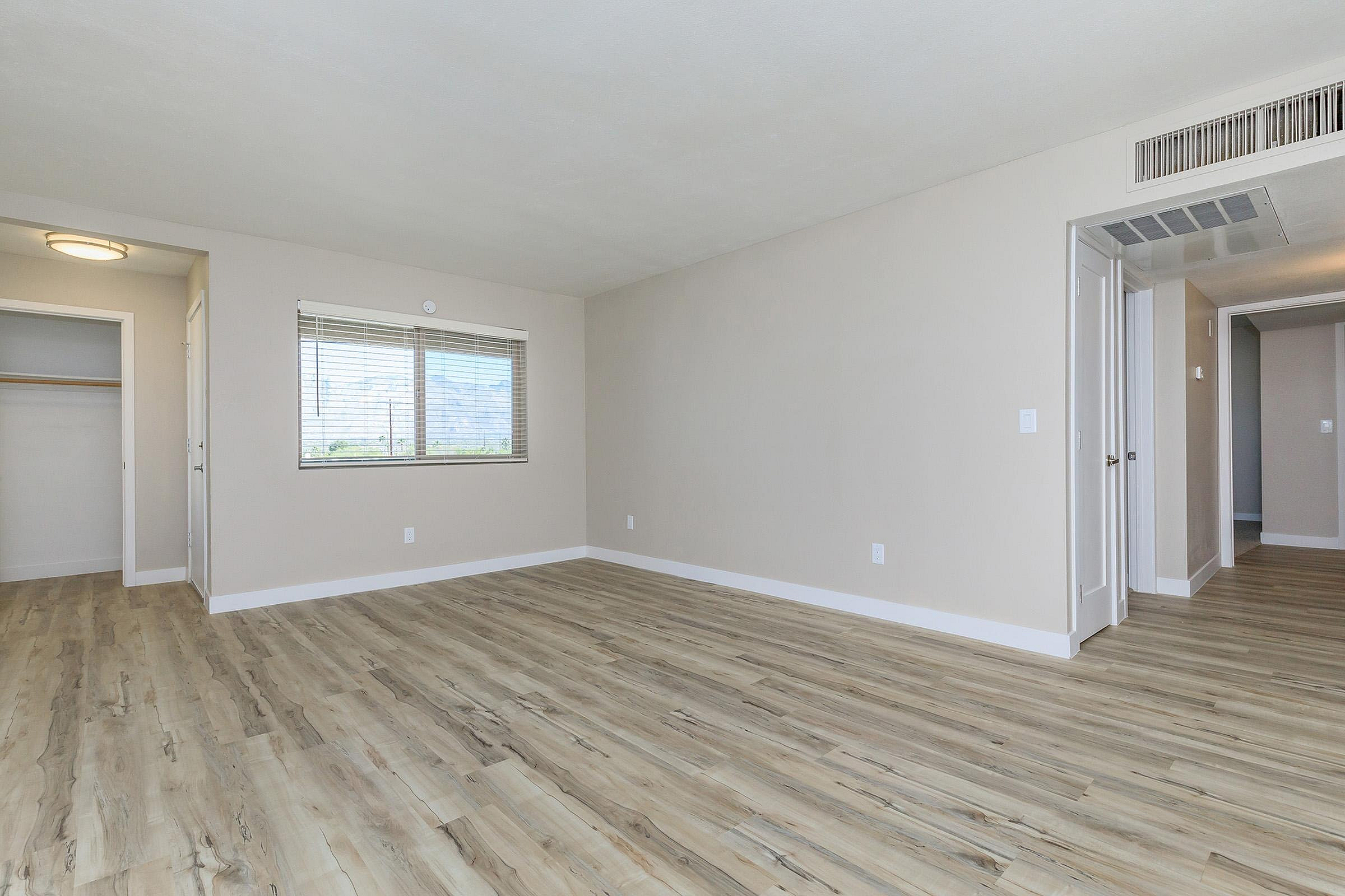 Bright and spacious room with modern wood flooring, neutral walls, and ample natural light from large window.