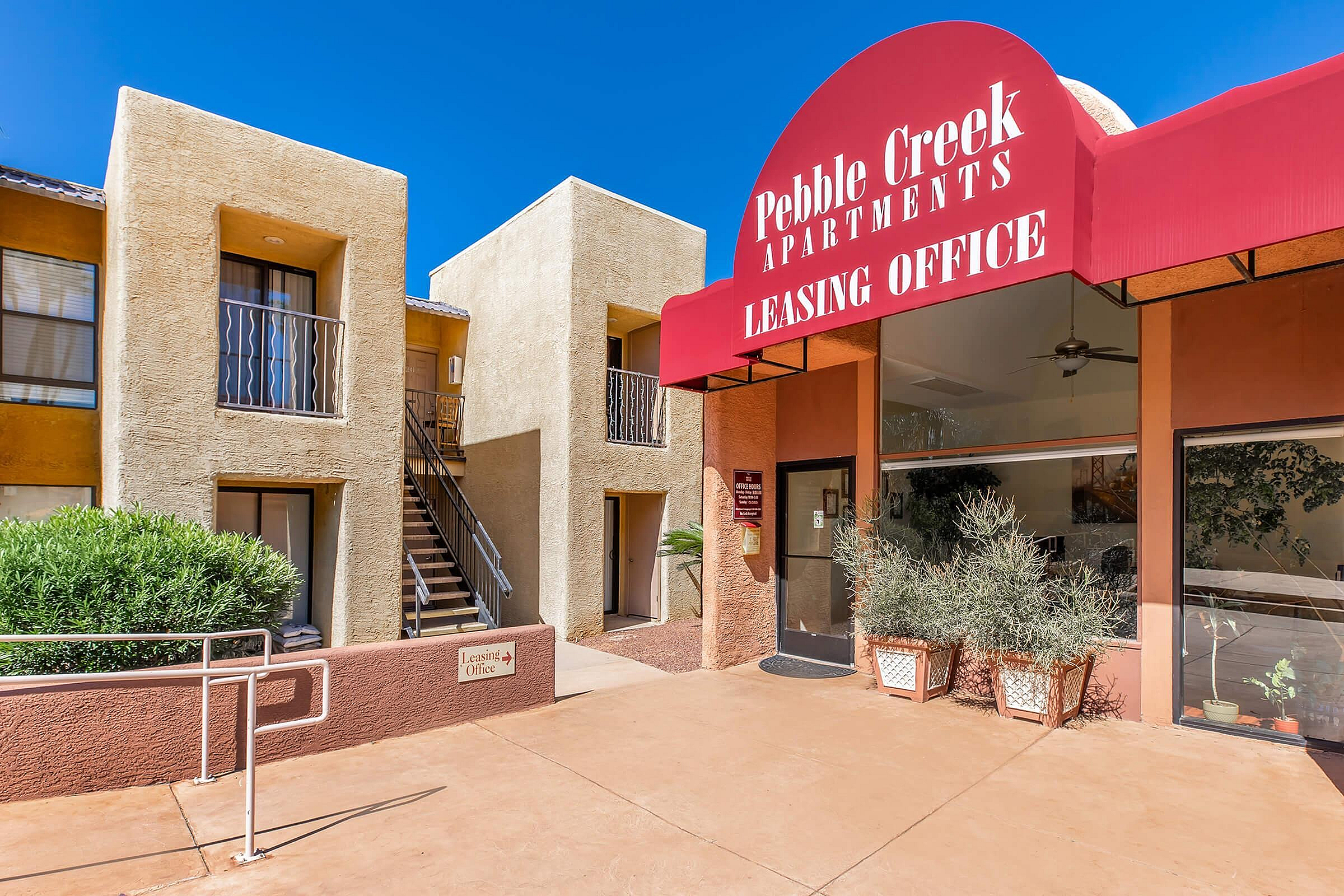 Inviting entrance to Pebble Creek Apartments featuring a welcoming leasing office with clear blue skies overhead.