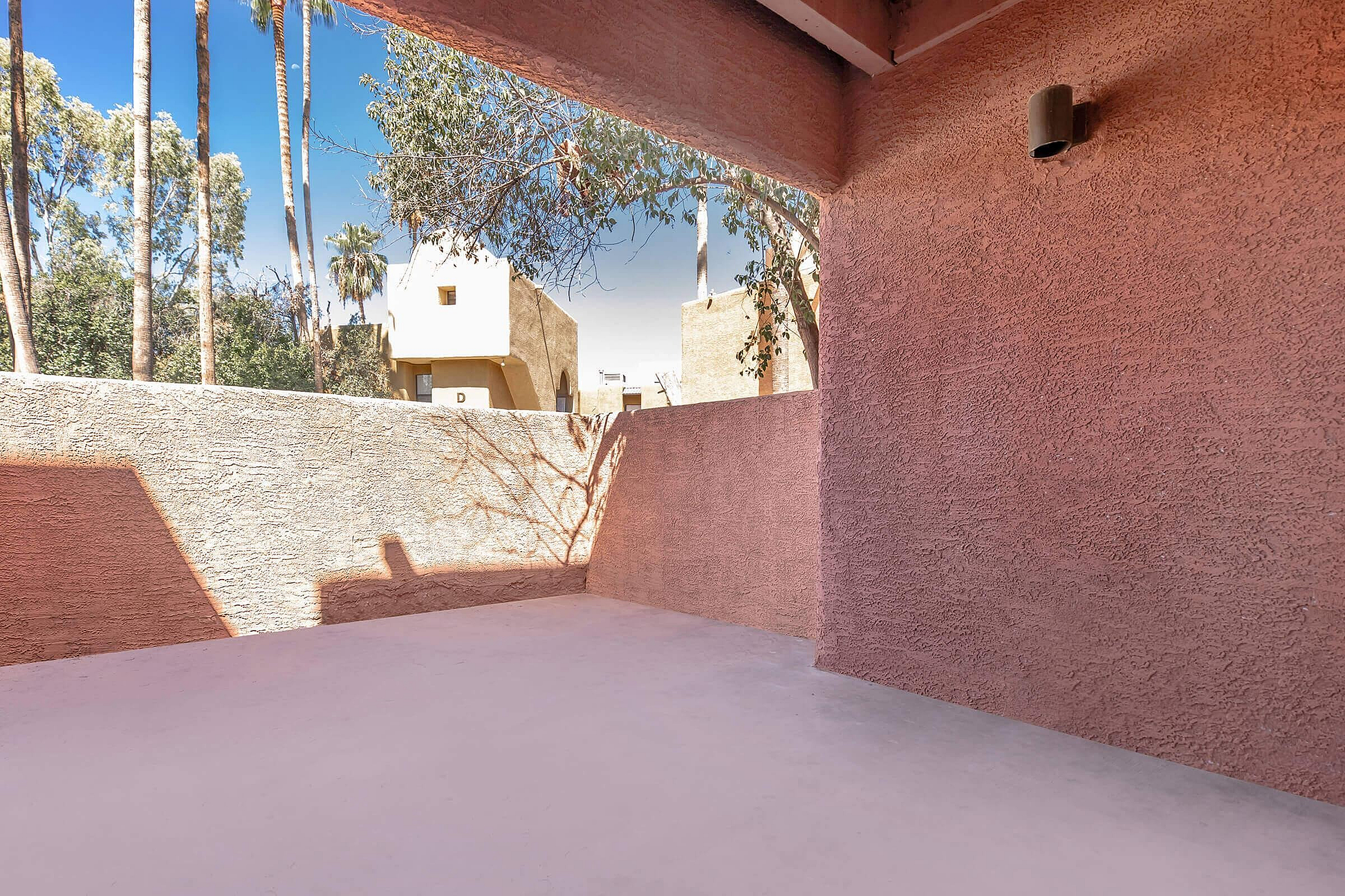 Charming outdoor patio with textured walls and scenic view of surrounding greenery and blue sky.