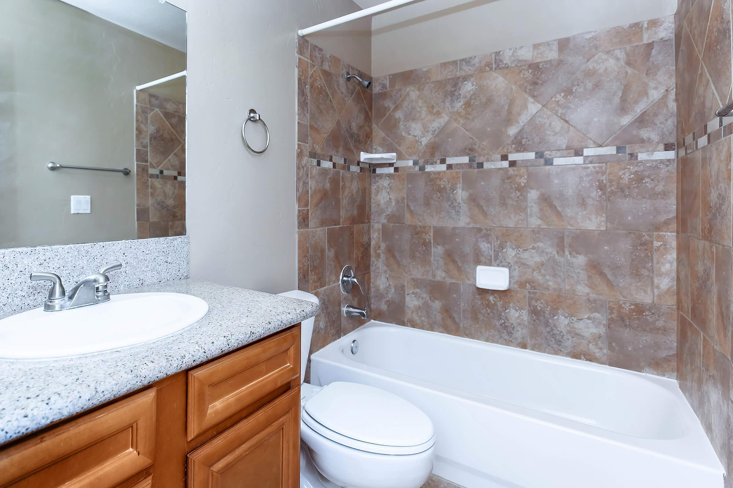 Elegant bathroom with a granite countertop, modern sink, and luxurious tile-finished shower and bathtub combination.