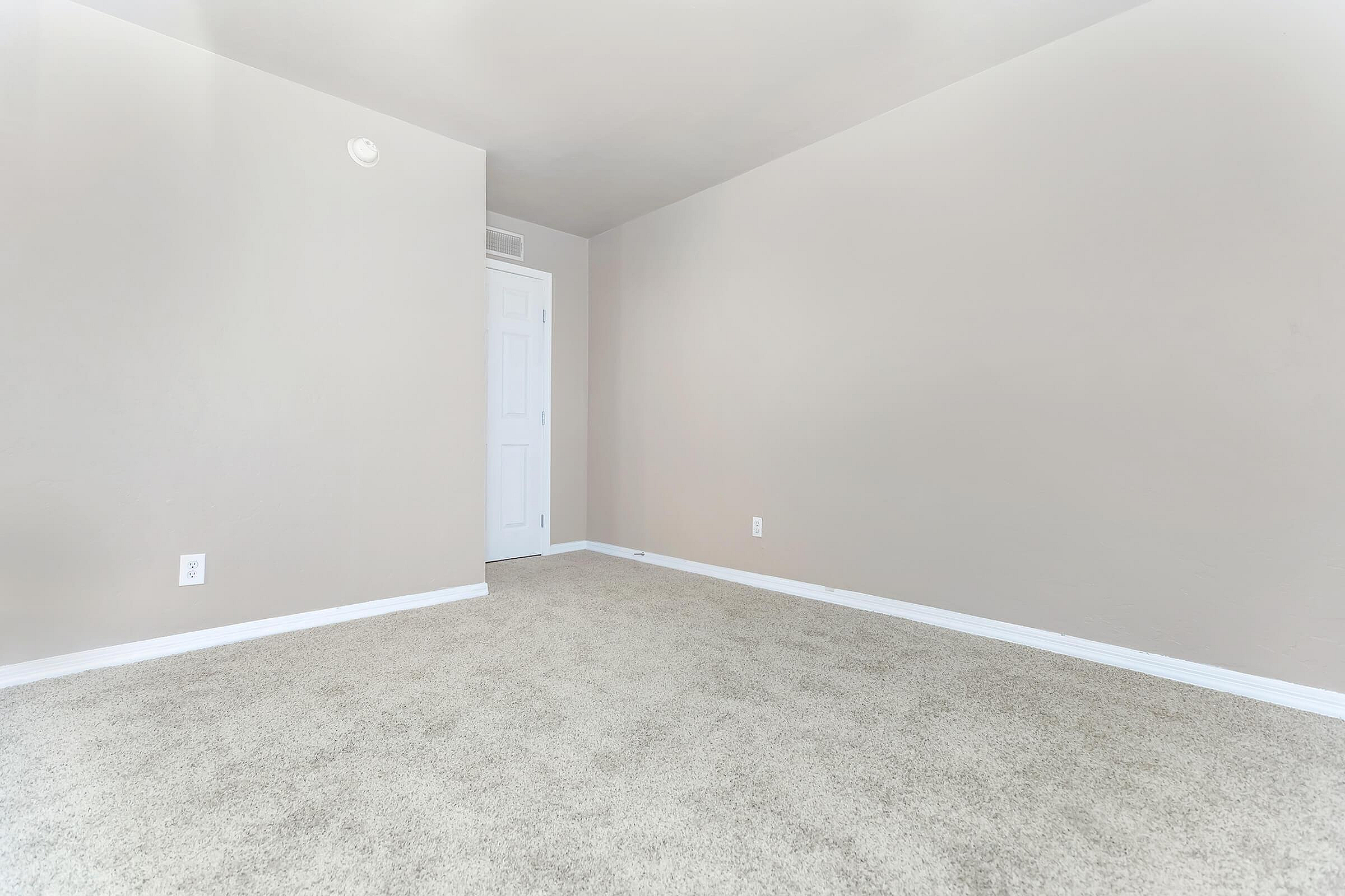 Inviting empty room with plush carpeting and neutral walls, ideal for customization.